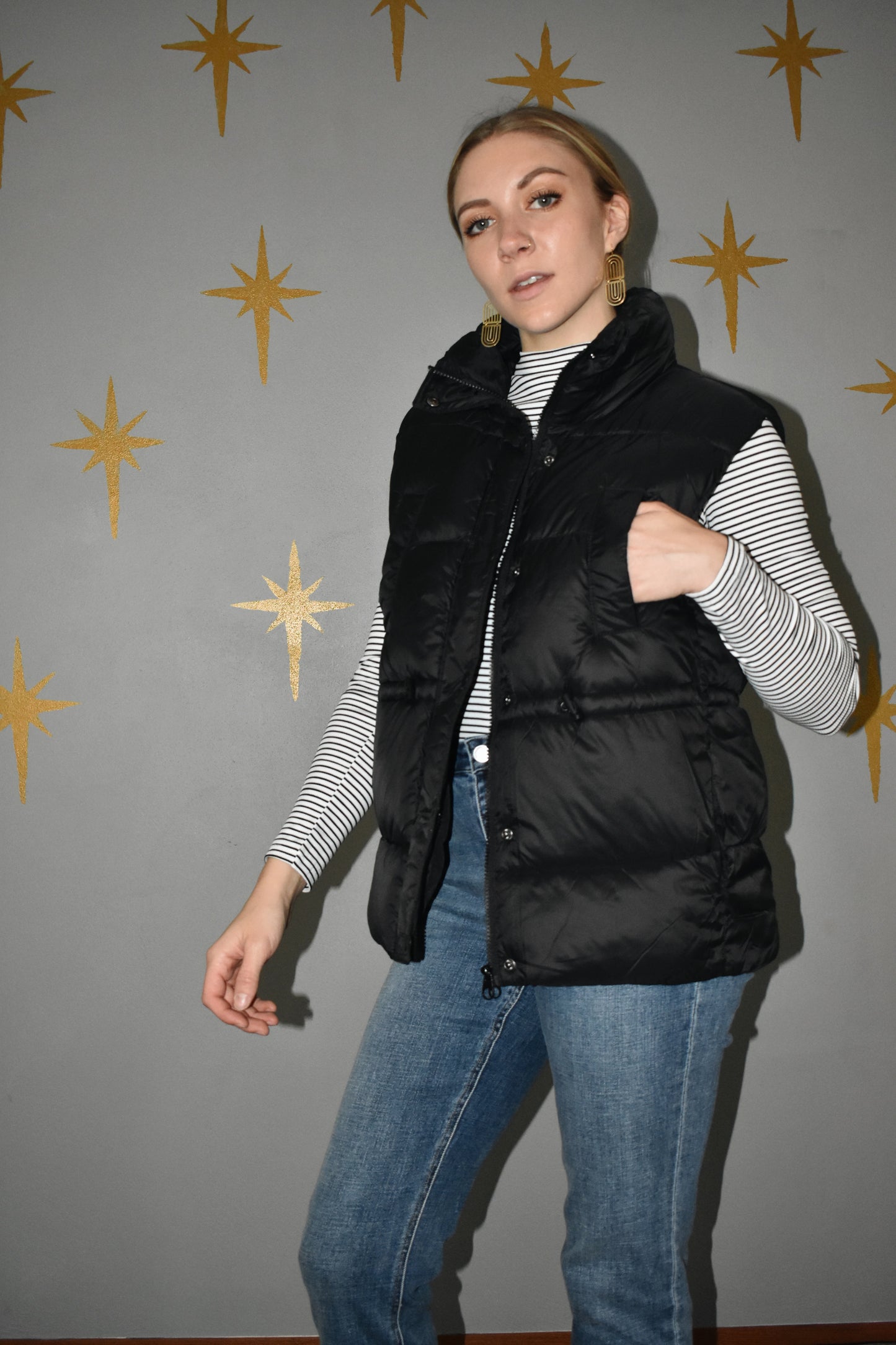 Lightweight zip up puffer vest with sinch drawstring around waist for adjustable fit. 4 pockets. Black.