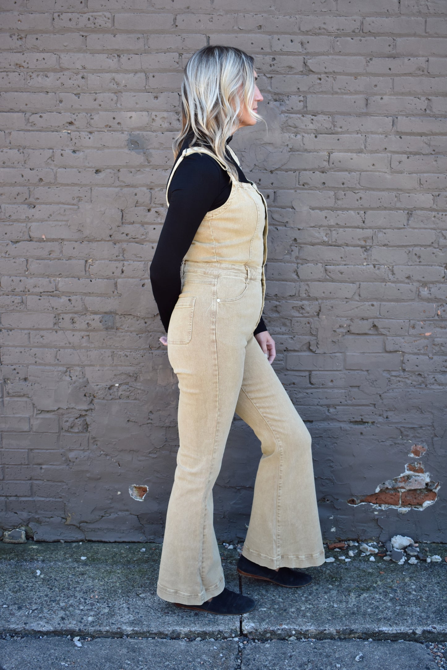tan fitted denim overalls with bell bottoms and buttons down the front. waistline band has beltloops and front and back pockets. Adjustable straps.