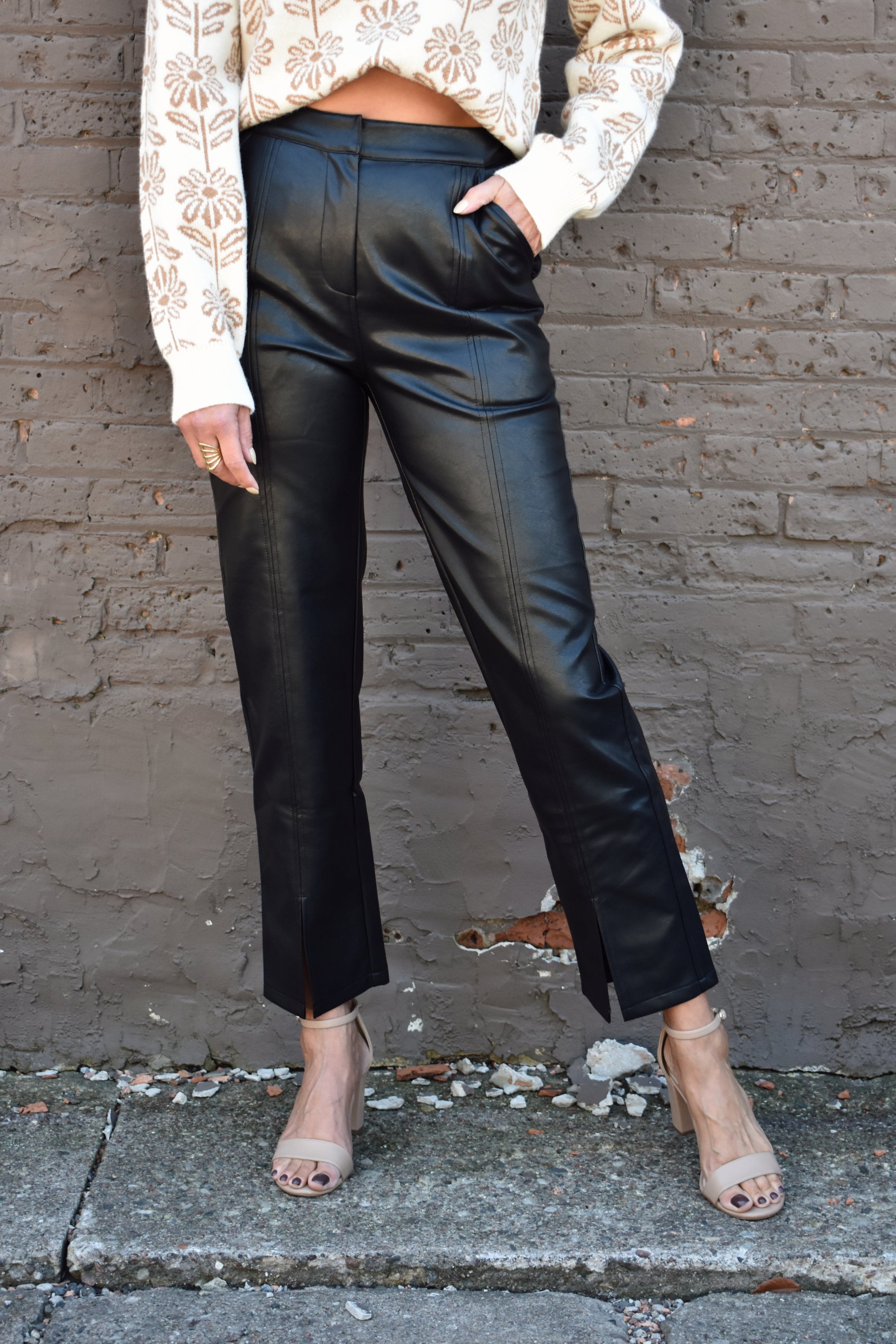black vegan leather pants straight fit, high waisted, side pockets, slit hem on the front part of the ankle, stitching detail down the middle of the pant legs on the front. 