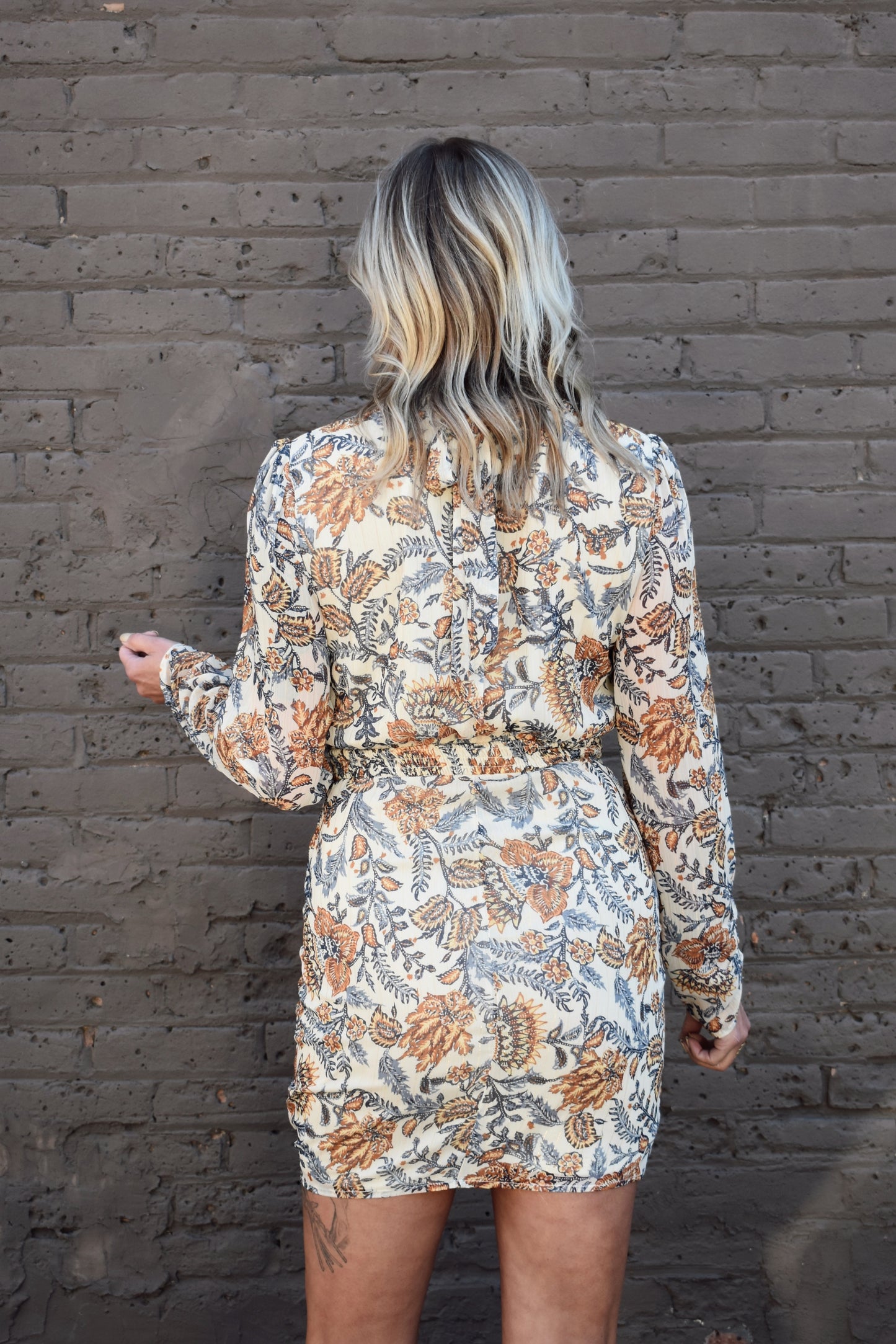 blue and taupe floral printed long sleeve mini dress with ivory background. Wrap skirt. mock neck with tie.