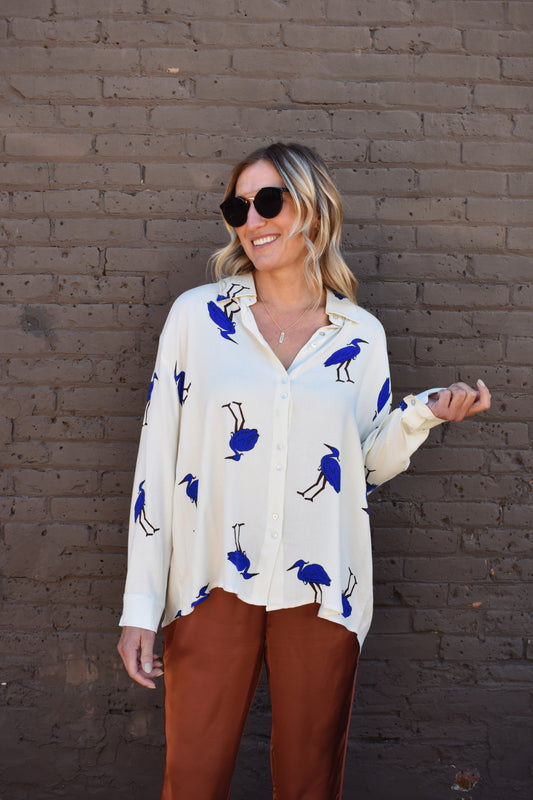 White relaxed fit button down with blue birds printed on it. High low hem. Drop shoulders.