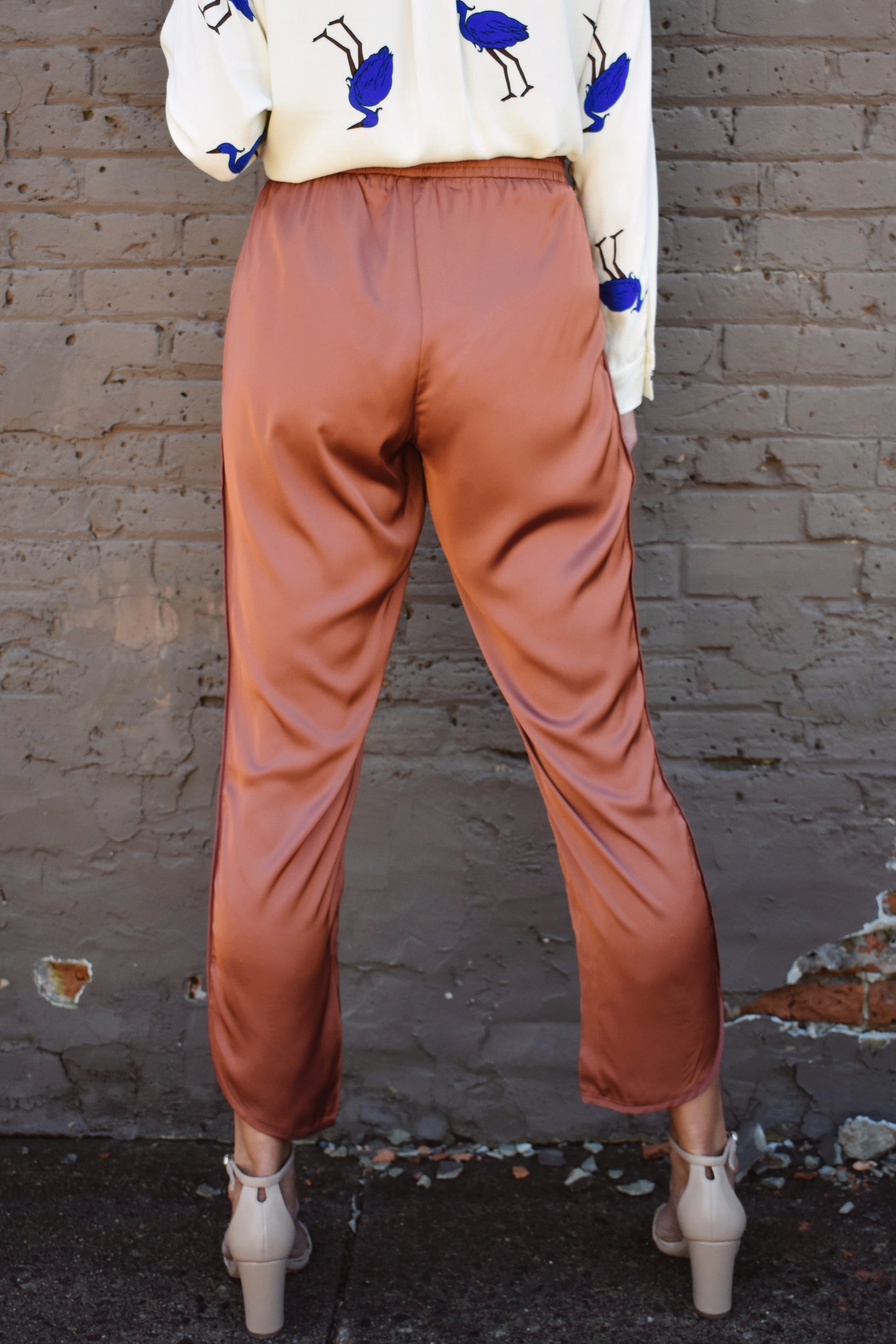 Copper colored satin joggers with side pockets and elastic waistband. rounded tulip hem with welted side seams.