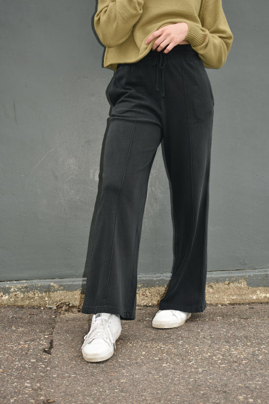 black wide leg athleisure pants with elastic waistband with drawstring, pockets and seam detail down the front of the legs.
