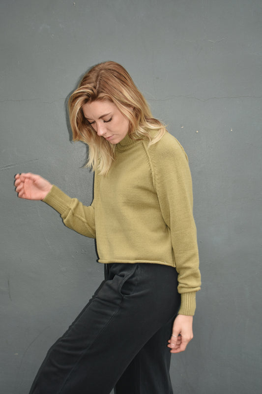 olive long sleeve turtleneck sweater with raw edge hem, along with exposed seam detailing on the front and back. ribbed turtleneck and ribbed fitted cuffs