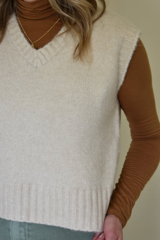 V neck sweater vest - slightly cropped, loose fit. Wide ribbed detail on neckline, sleeves and hem. Cream colored.