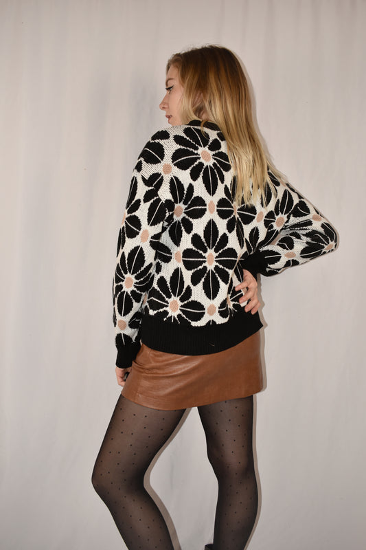 floral tile loose fitting sweater with drop shoulders and black trim. Full length with white background and black flowers with taupe accent dots. 