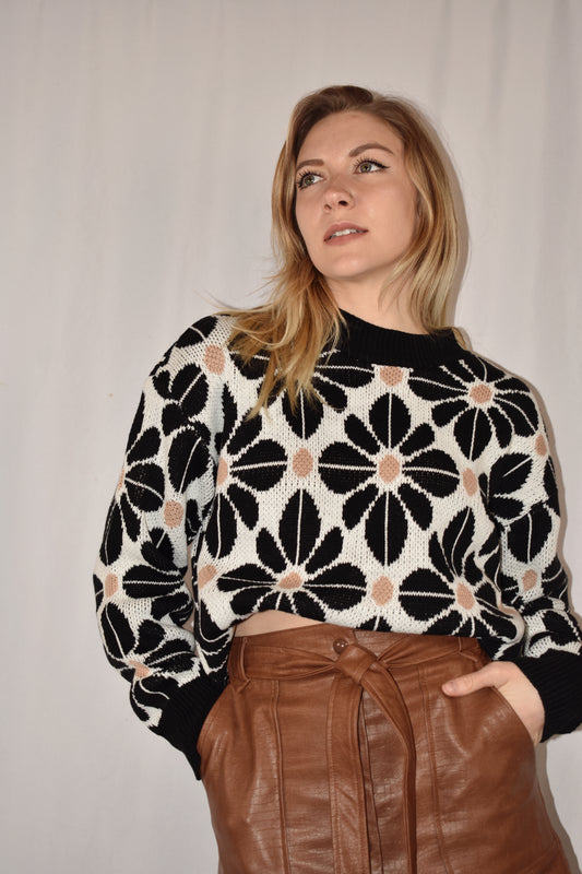 floral tile loose fitting sweater with drop shoulders and black trim. Full length with white background and black flowers with taupe accent dots. 