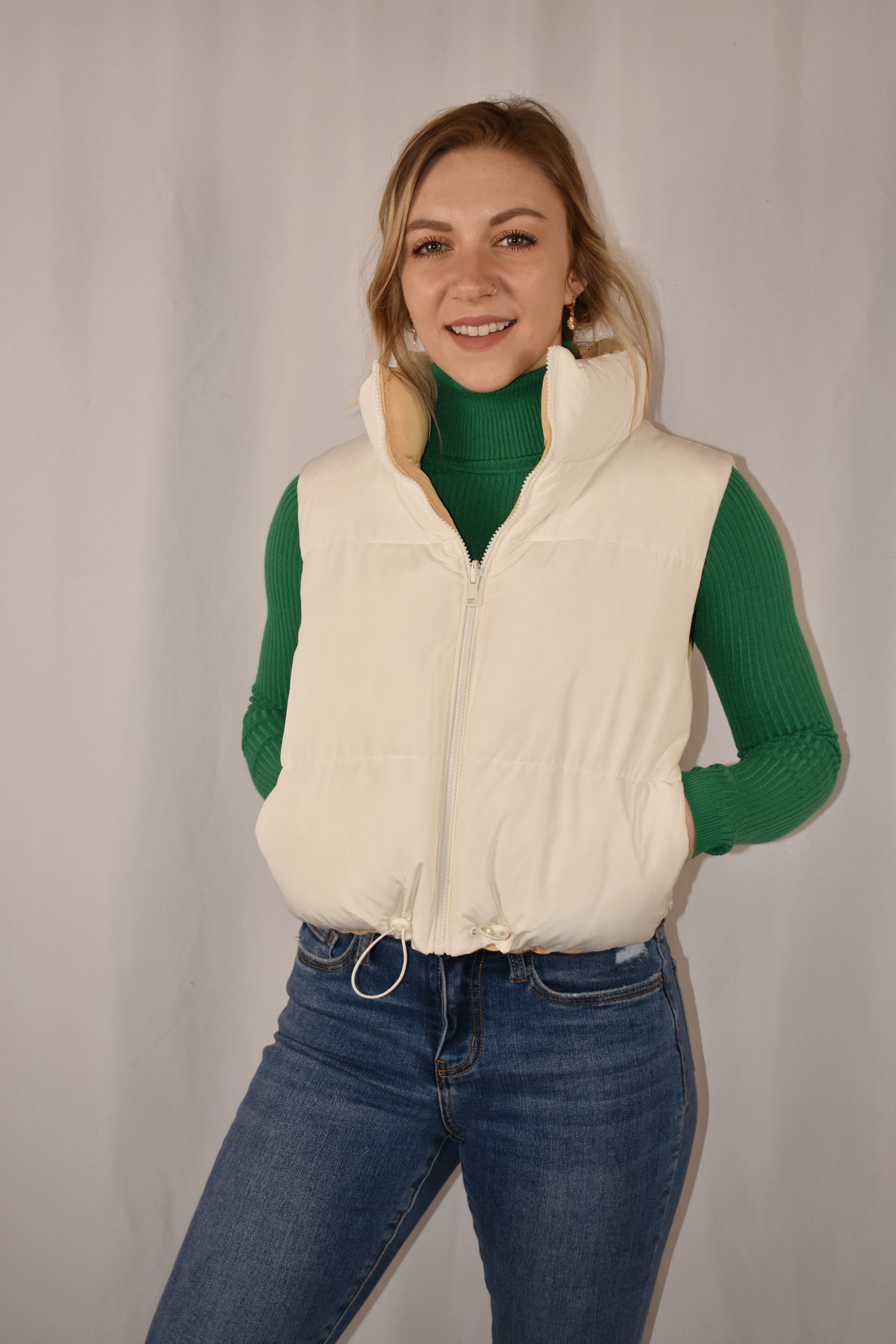 reversible waist length puffer vest with collar, zip front, side pockets, and draw string at bottom.
