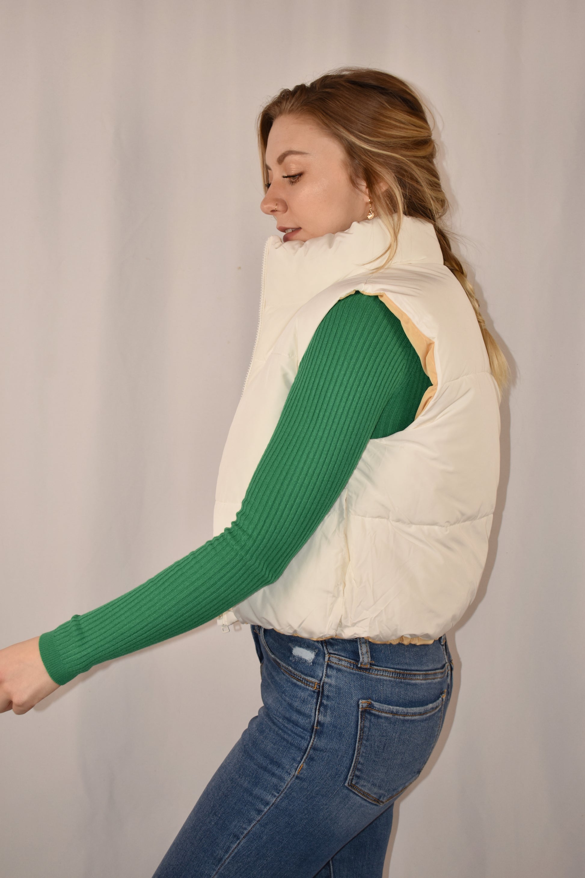 reversible waist length puffer vest with collar, zip front, side pockets, and draw string at bottom.