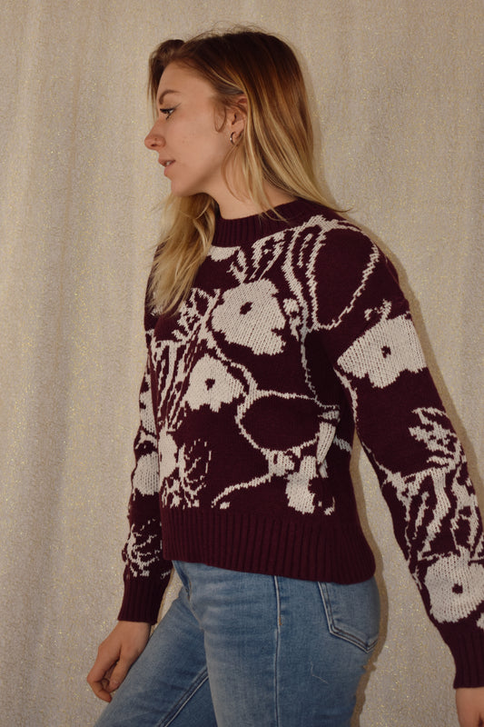 deep purple sweater with white floral pattern. ribbed cuffs hem and neckline. crew neck. waist length