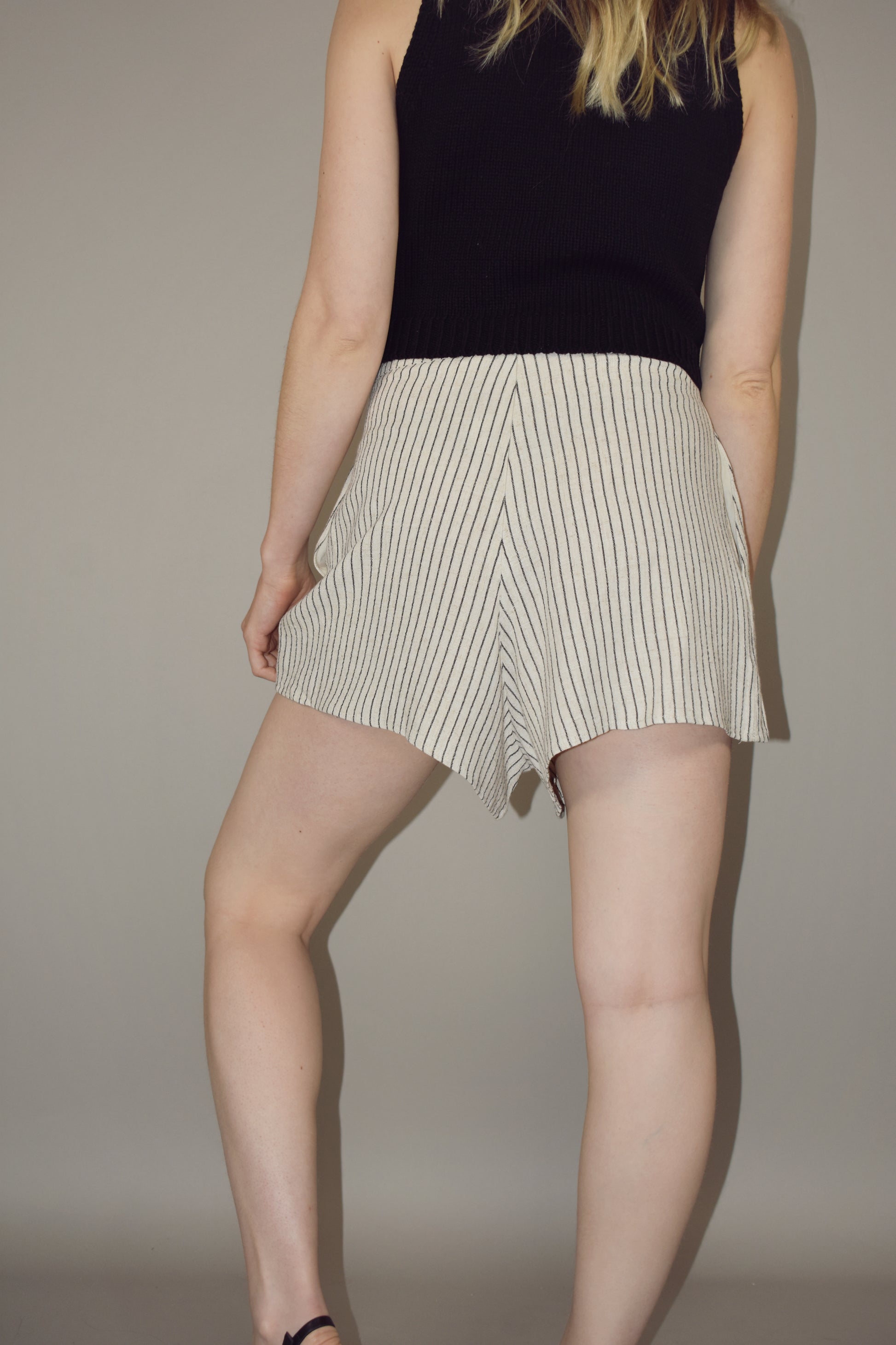 linen shorts with side pockets and zip enclosure in back. cream with black vertical pin stripes. mid thigh length.