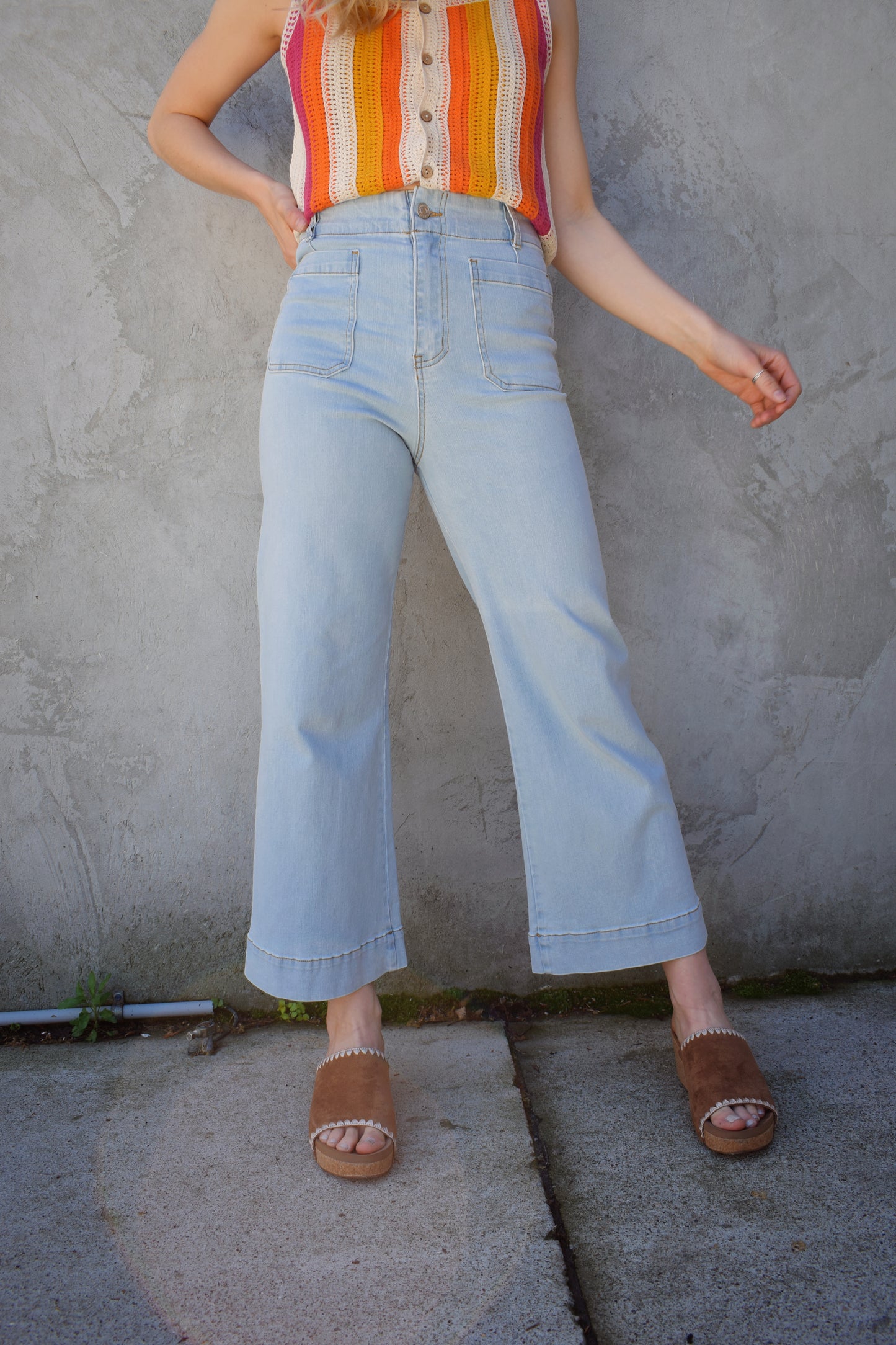 wide leg slightly cropped light wash jeans with front patch pockets. back pockets. zip and button enclosure. no holes. stretch denim. high waisted. seam detailing on back waistband area.