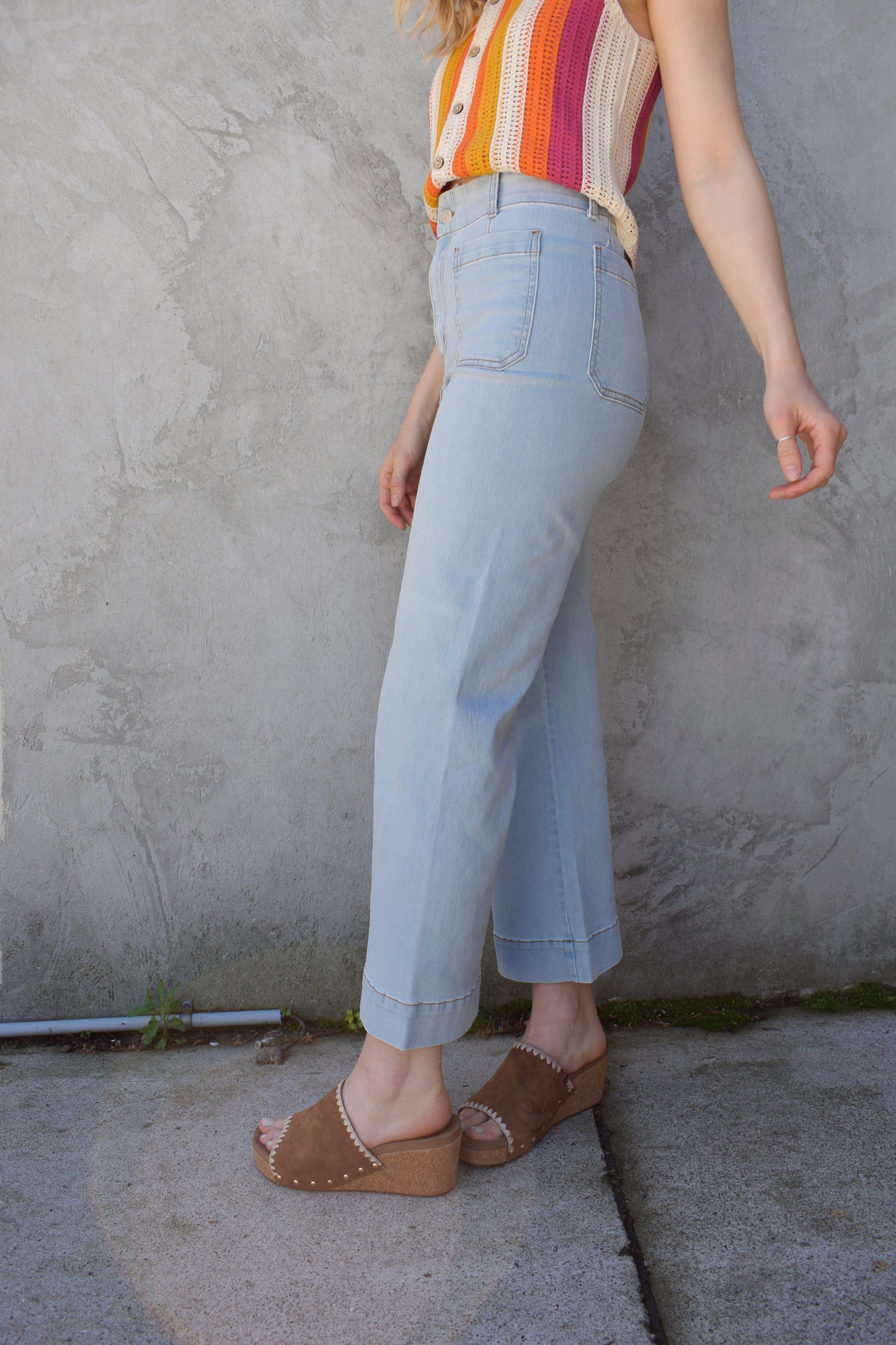 wide leg slightly cropped light wash jeans with front patch pockets. back pockets. zip and button enclosure. no holes. stretch denim. high waisted. seam detailing on back waistband area.