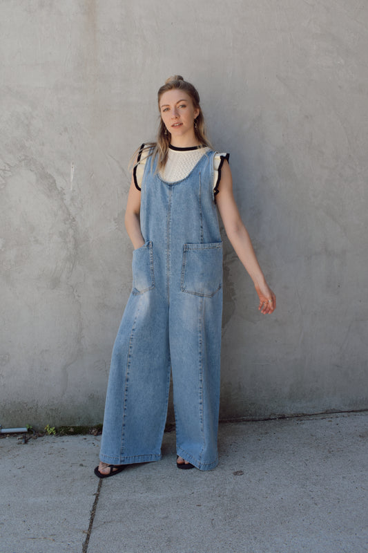 extra roomy wide leg denim overalls with scoop neckline, adjustable straps, front patch pockets, seam detail down front of bodice and pant legs. run slightly long. thick straps. medium-light wash with no distressing. low scoop back