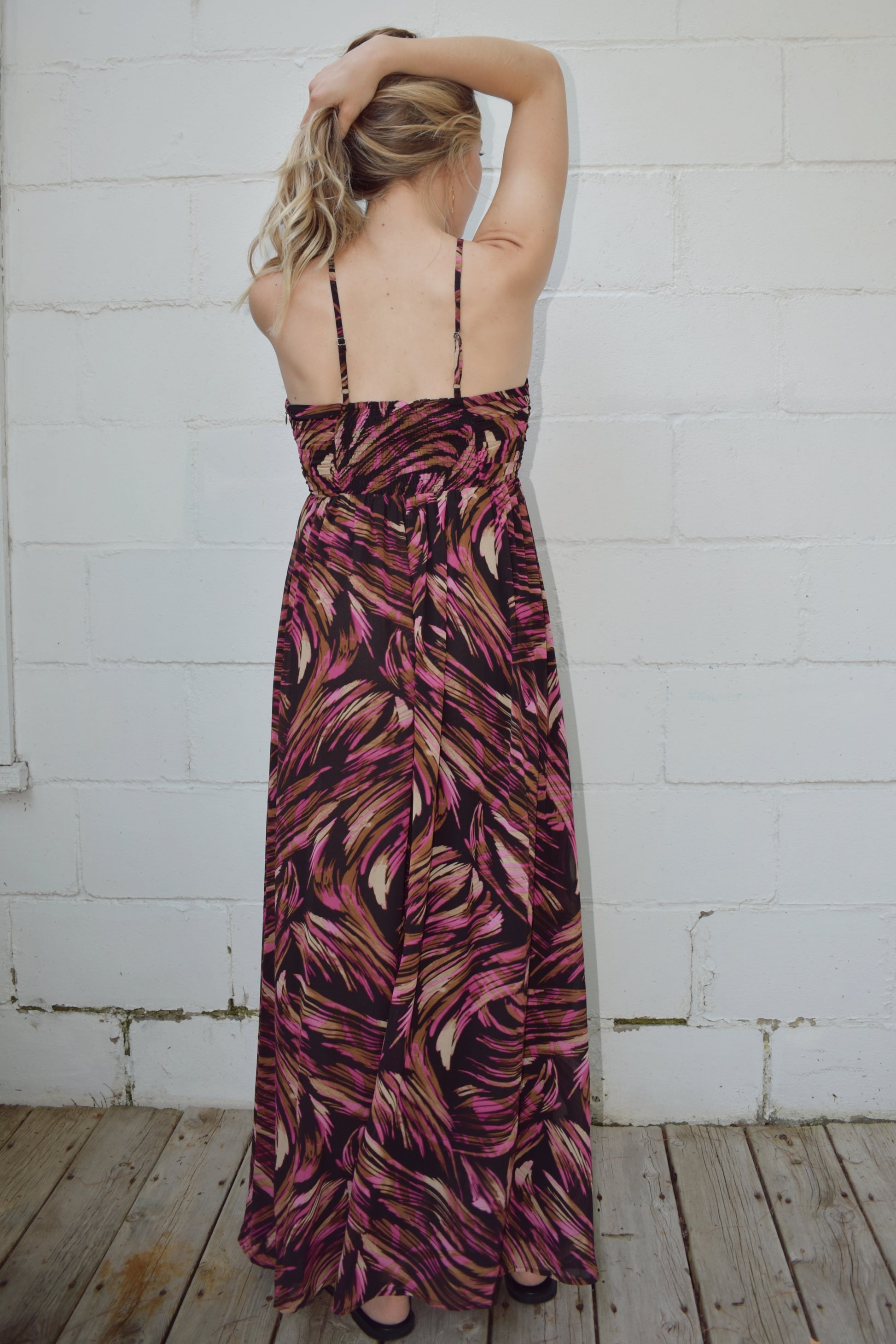 maxi dress with black background and a fuchsia wavy/swirl print. spaghetti straps cross and meet in middle of front with synched bra area with tassel. adjustable straps 