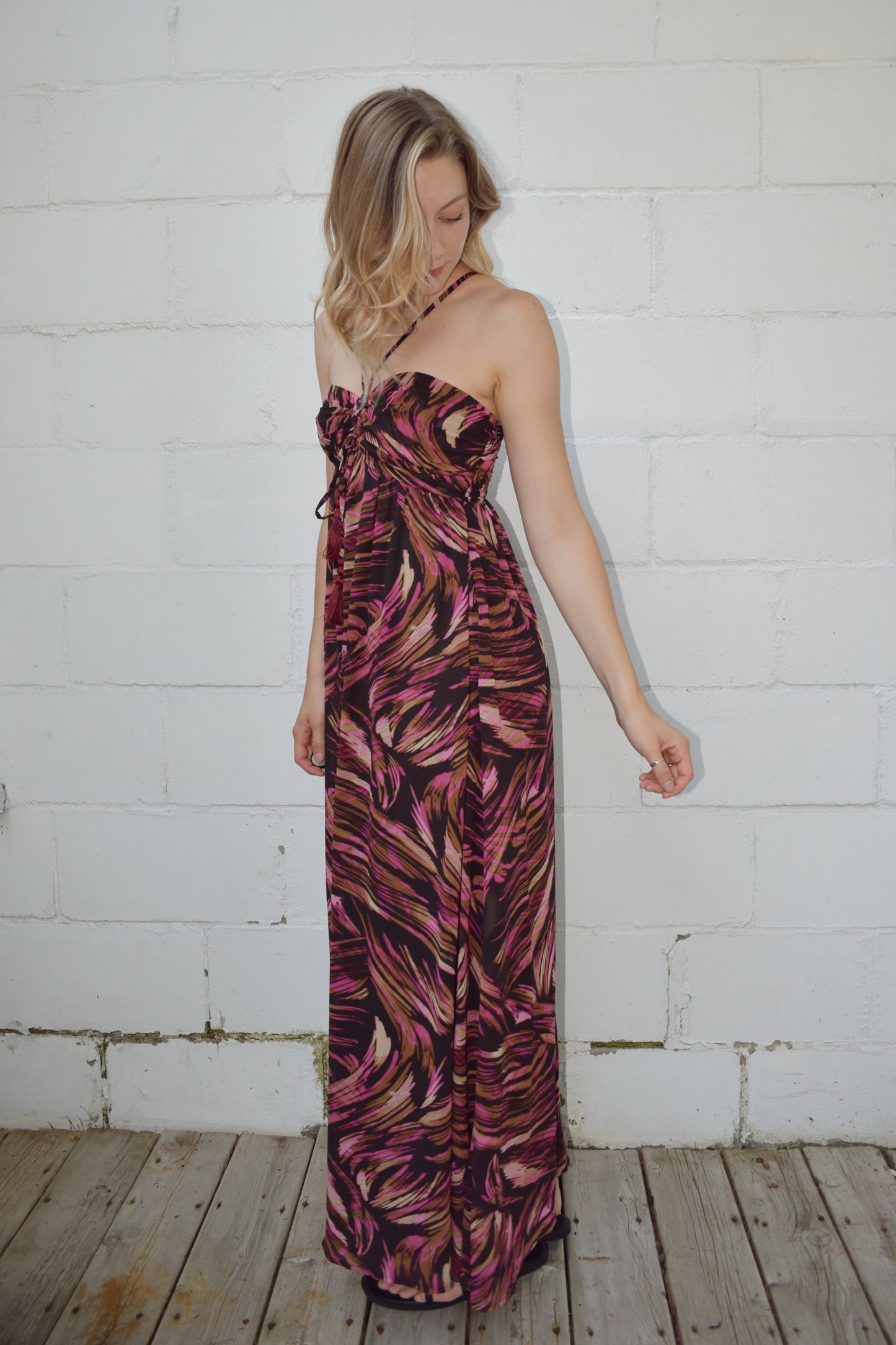 maxi dress with black background and a fuchsia wavy/swirl print. spaghetti straps cross and meet in middle of front with synched bra area with tassel. adjustable straps 