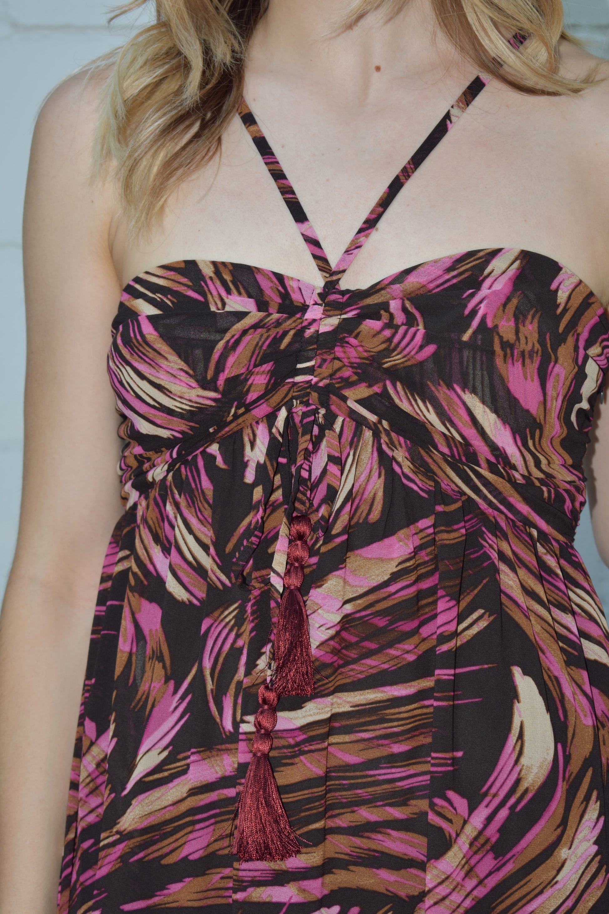 maxi dress with black background and a fuchsia wavy/swirl print. spaghetti straps cross and meet in middle of front with synched bra area with tassel. adjustable straps 