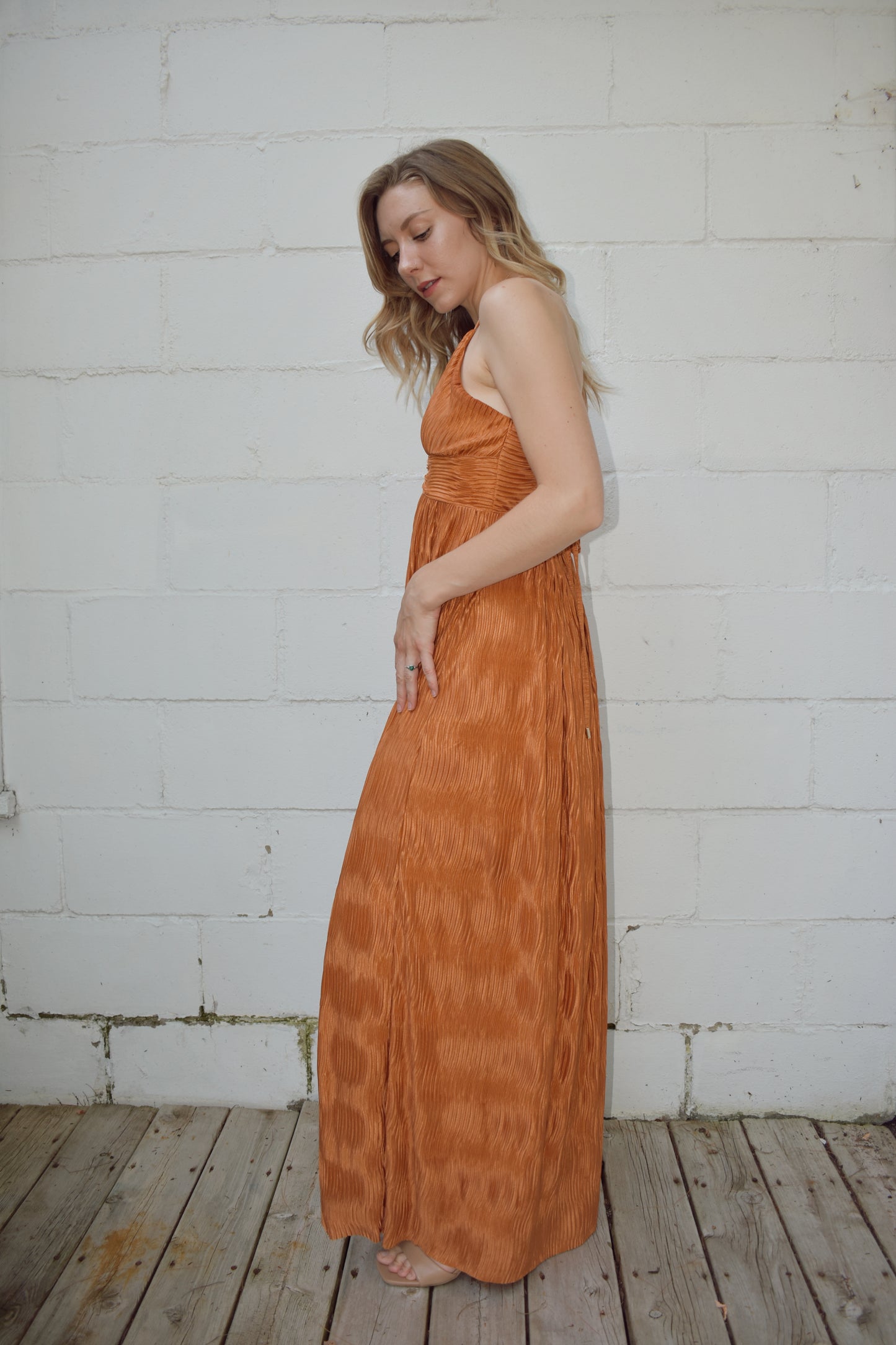 deep v neck spaghetti strap dress with a wavy texture fabric that illuminates when in the sun. maxi dress. straps cross in the back and tie which features a triangle cutout. theres a metal bar that connects the band just under the neckline.