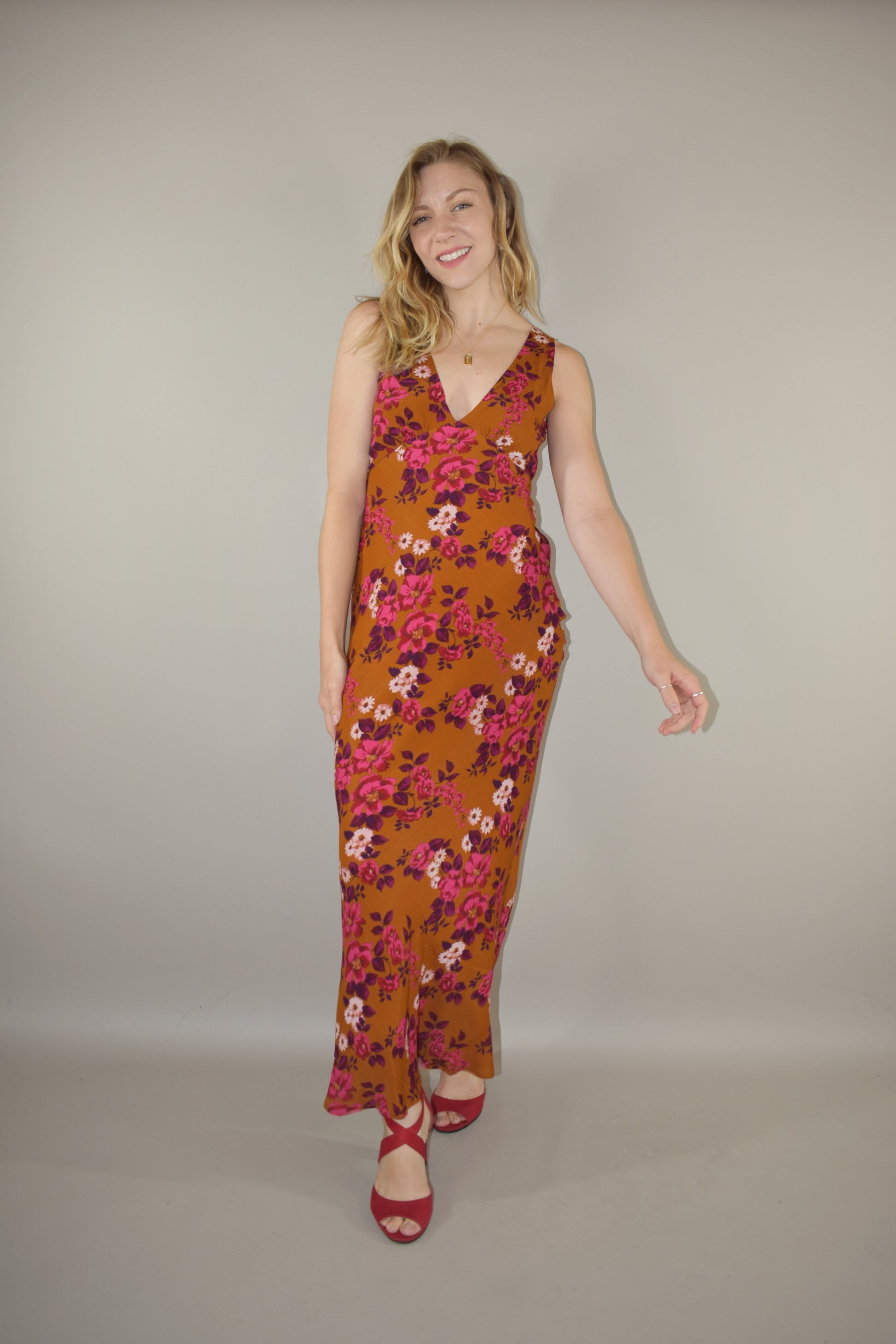 elegant floral maxi dress, v front and back neckline, more fitted through bodice and hips, skinny tie at waist that ties in the back, hidden side zip enclosure. Rust, pink, plum, fuchsia and white colors.