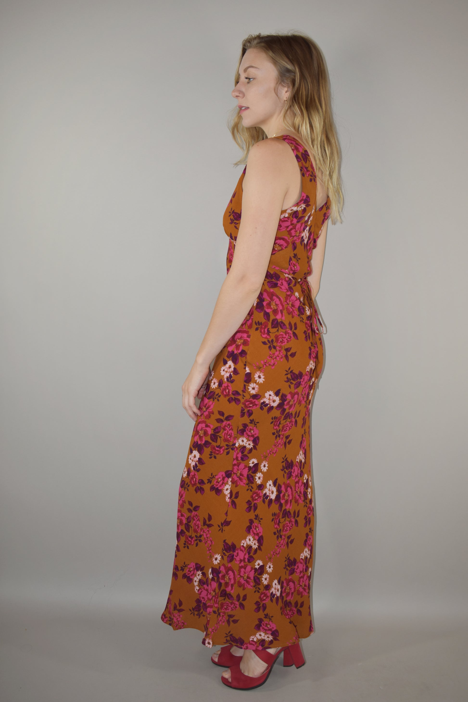 elegant floral maxi dress, v front and back neckline, more fitted through bodice and hips, skinny tie at waist that ties in the back, hidden side zip enclosure. Rust, pink, plum, fuchsia and white colors.