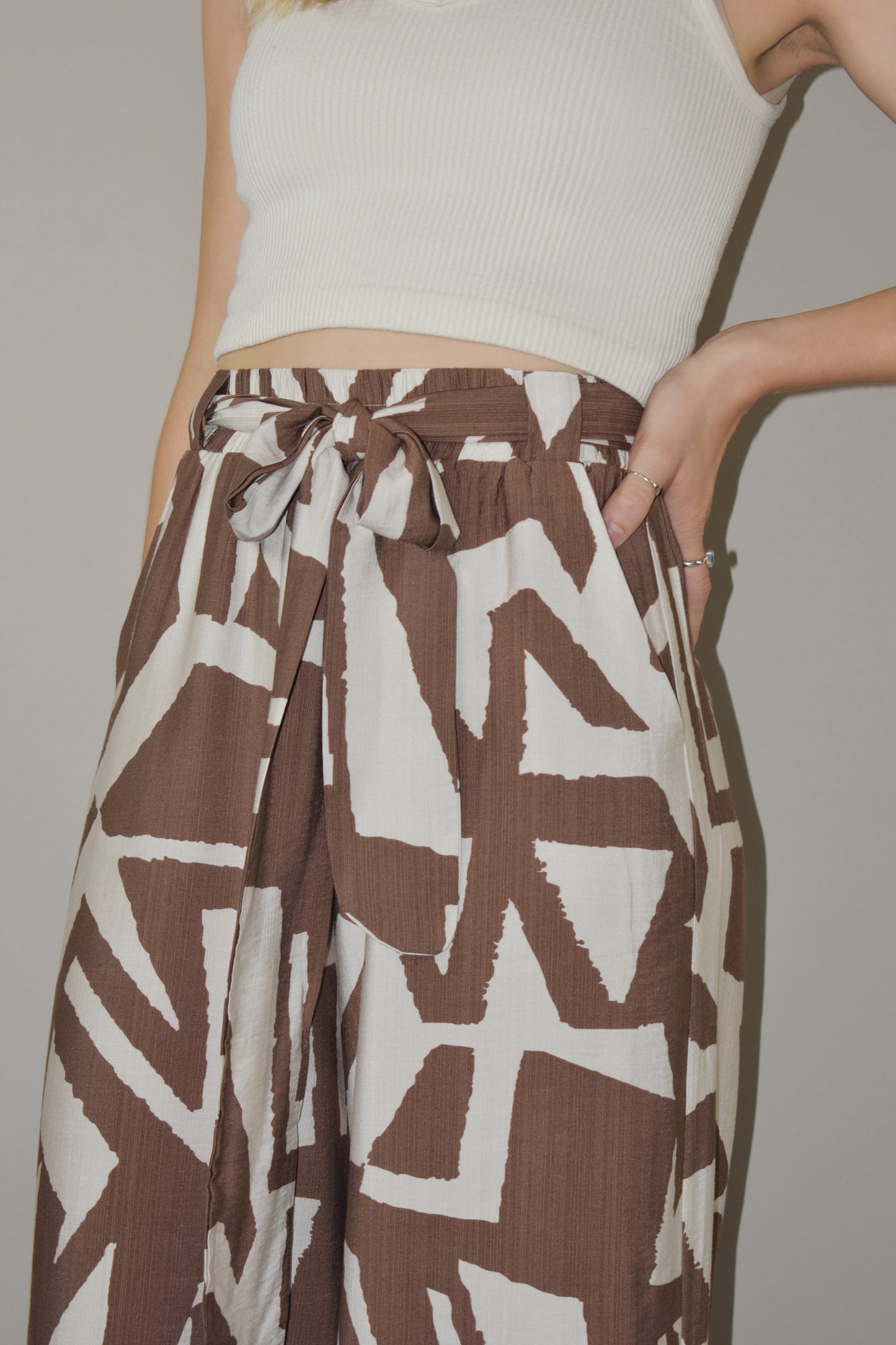 wide leg high waisted belted tie waist pants. flowy light weight fabric. cream and light brown geometric print. has pockets. full length.