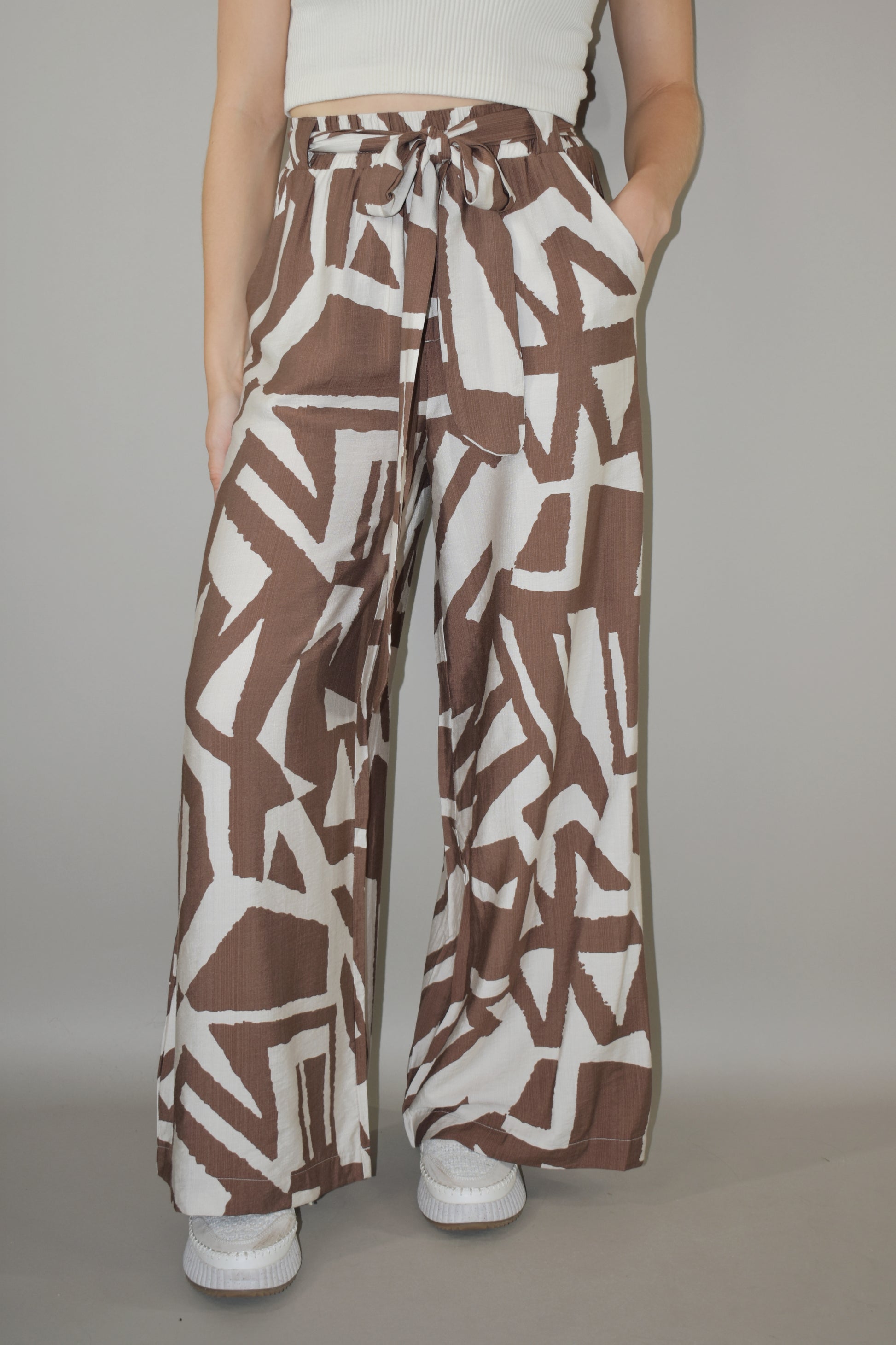 wide leg high waisted belted tie waist pants. flowy light weight fabric. cream and light brown geometric print. has pockets. full length.