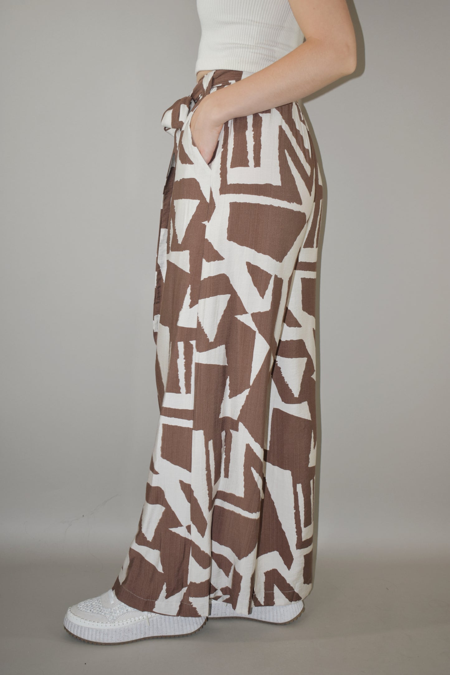 wide leg high waisted belted tie waist pants. flowy light weight fabric. cream and light brown geometric print. has pockets. full length.