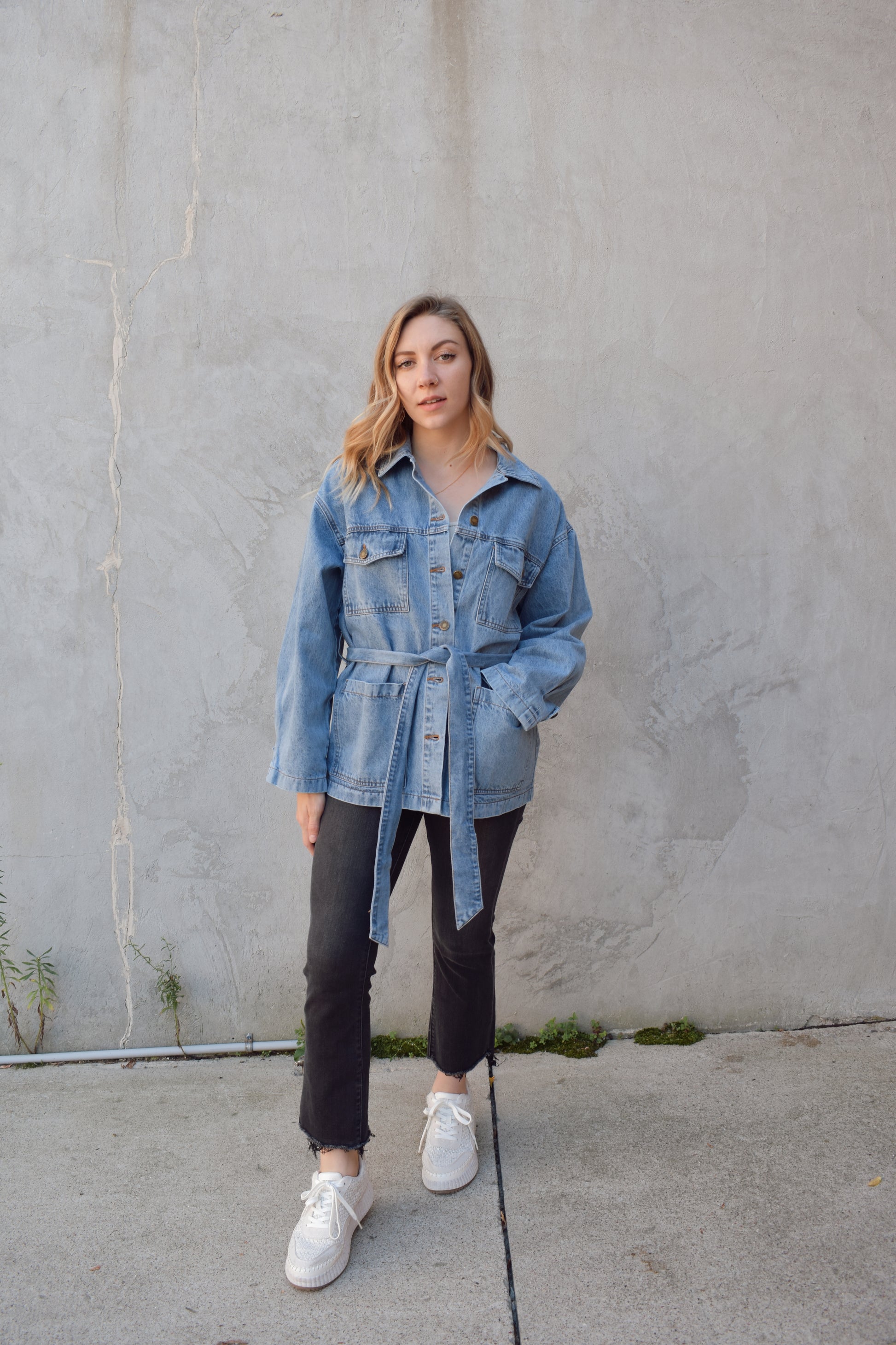 medium wash denim jacket with relaxed fit, tie at waist, deep patch pockets along with breast pockets with flap and button enclosure