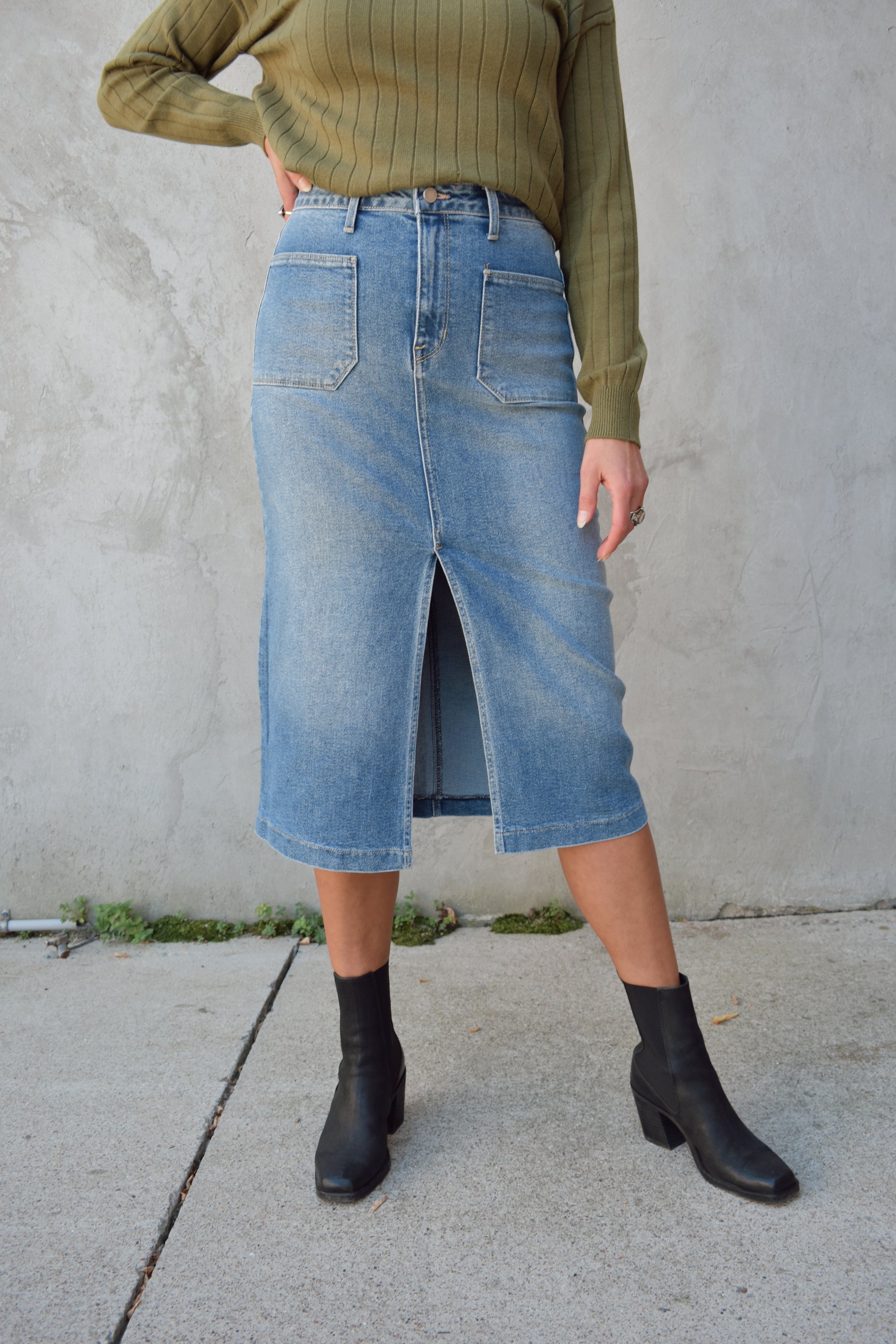 medium to light wash denim midi skirt with front slit, front patch pockets, zip and button enclosure, beltloops, back pockets, no distressing.