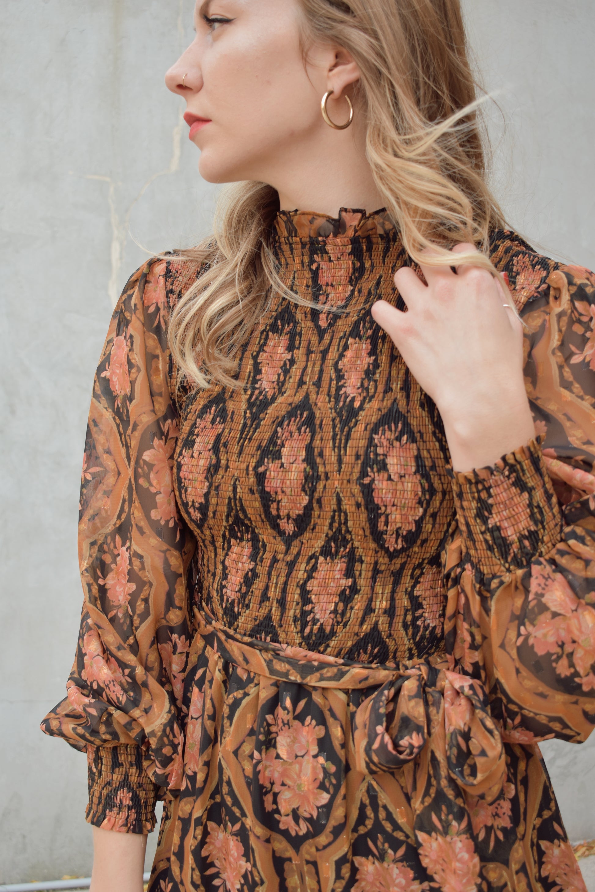 long sleeve high/mock neck midi dress with smocked bodice and cuffs, sheer sleeves, flowy skirt, fabric tie at waist, floral boho tapestry pattern. double button at back of neck