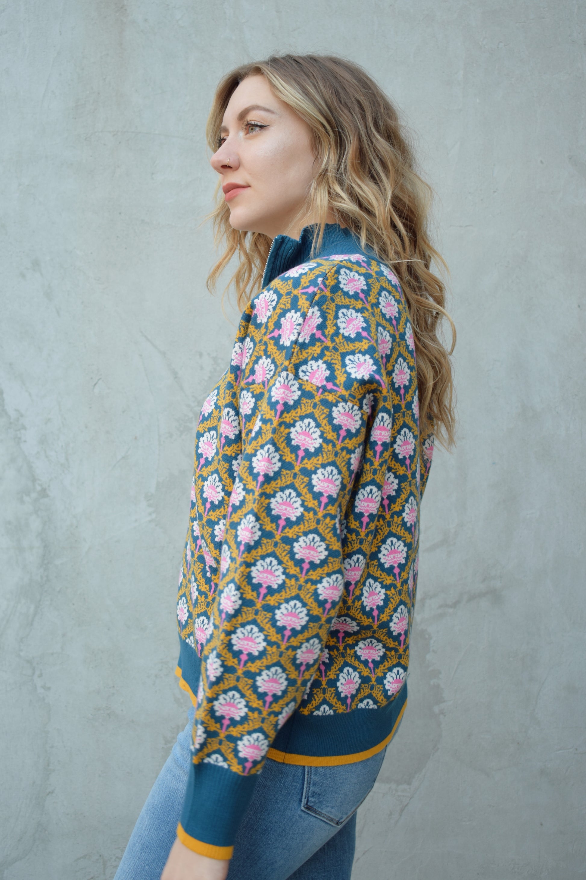 half zip relaxed fit statement pattern pullover with blue and yellow band at ham and cuff and just blue on collar. pattern is yellow, white, and pink on a blue background