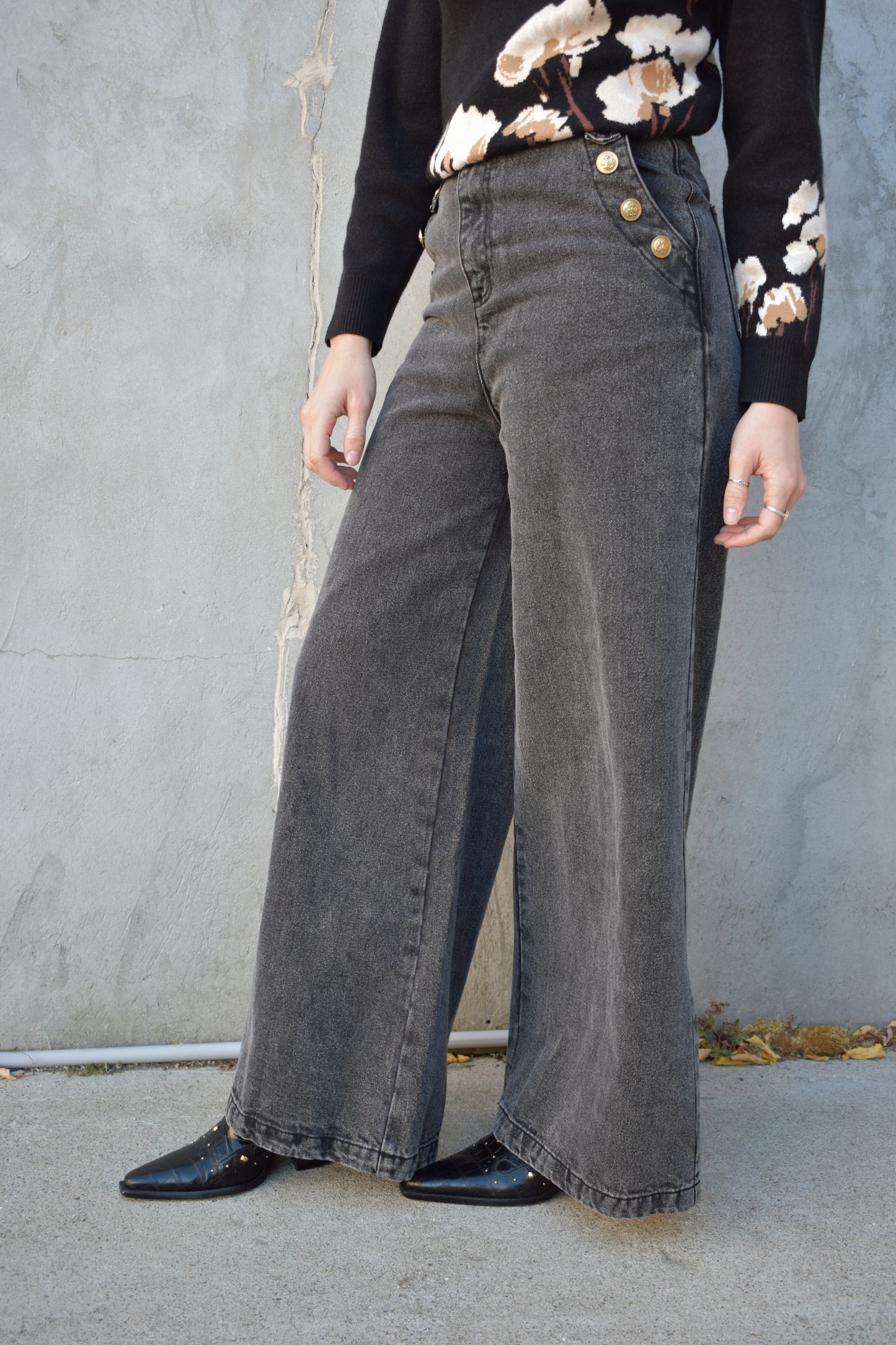 wide leg jeans - black wash - no holes - gold sailor buttons along front side pockets and on button on back belt loop fastening it. zip and button enclosure. high waisted. 