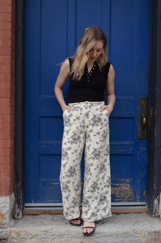 cream wide leg trousers with slate blue floral pattern, zip and button enclosure, front and back pockets, has beltloops, cuffed hem, high rise, statement pants, 100% cotton