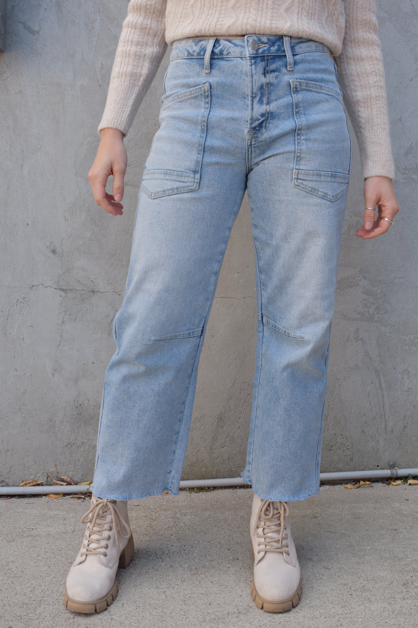 high rise barrel jeans, light wash, stretch denim, no holes, patch pockets in front, back pocket on right has a double pocket detail, zip and button enclosure, has belt loops, raw hem cropped, edgy seam detail at knee