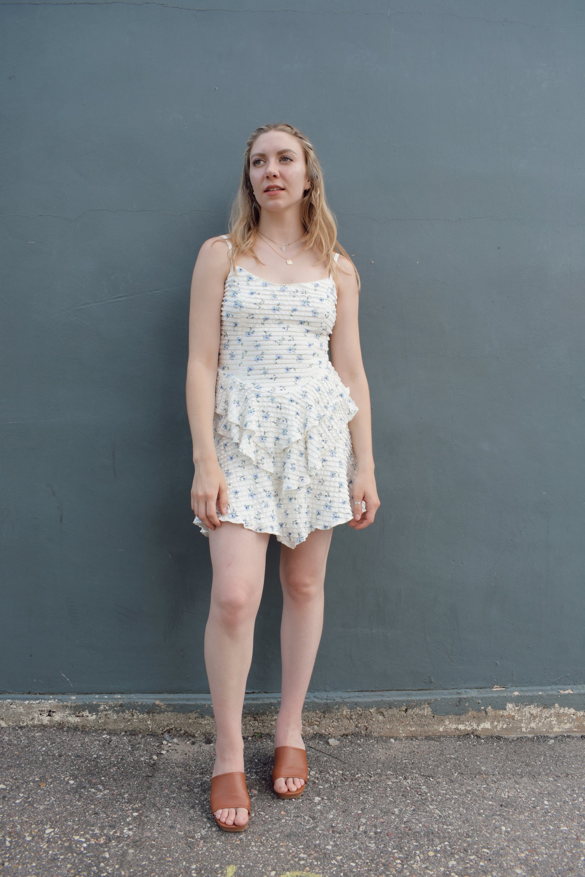 cream mini dress with a blue ditsy floral pattern and mini ruffle fabric, stretchy, back zip enclosure, adjustable spaghetti straps, shark bite tiered skirt, fitted bodice, lined