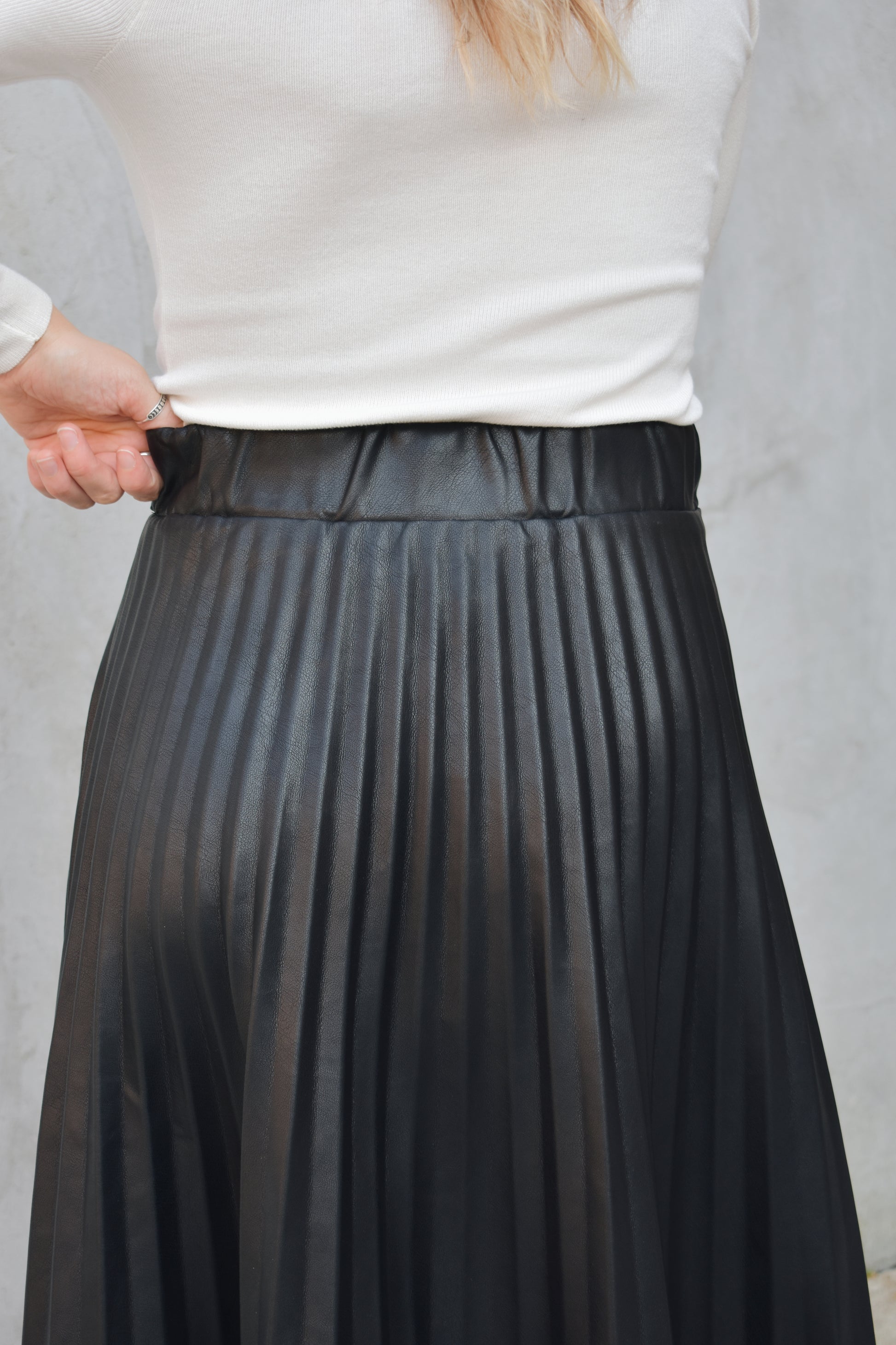 high waisted fully pleated faux leather skirt midi length waist band has tab detailing back of waistband has elastic in band for stretch and it has an invisible zip enclosure on the side