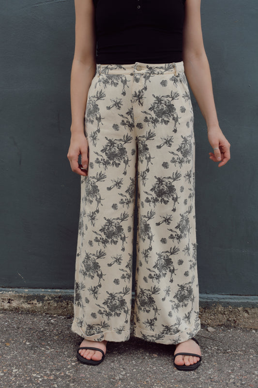 cream wide leg trousers with slate blue floral pattern, zip and button enclosure, front and back pockets, has beltloops, cuffed hem, high rise, statement pants, 100% cotton