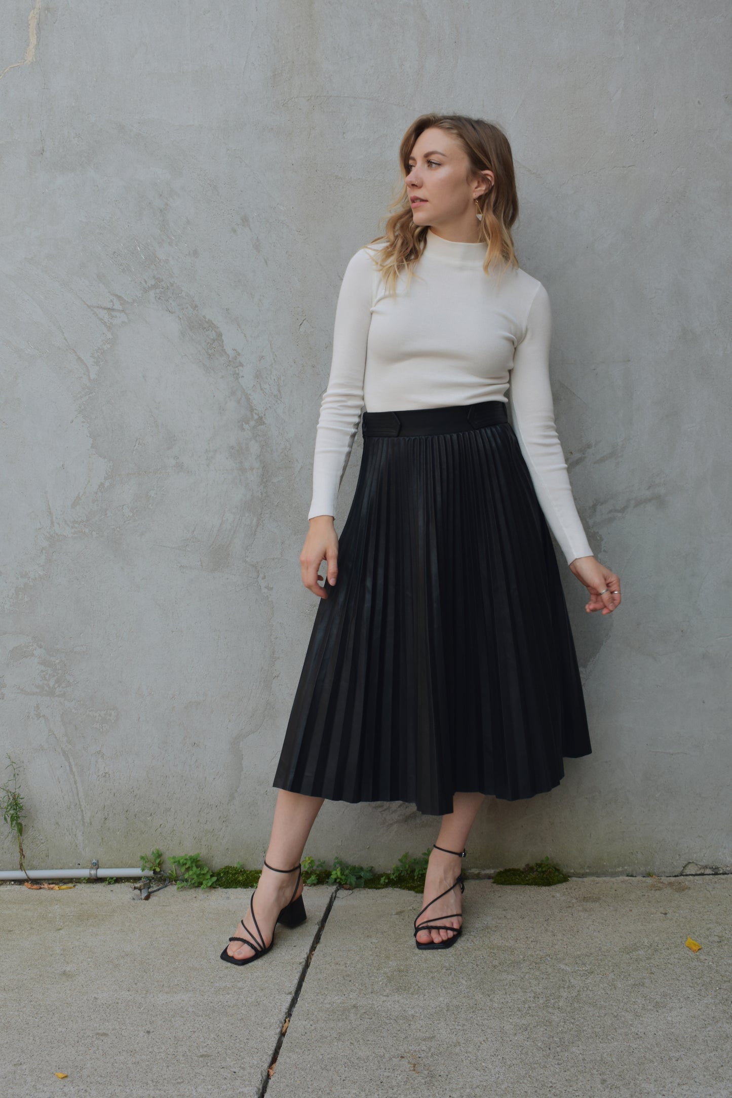 high waisted fully pleated faux leather skirt midi length waist band has tab detailing back of waistband has elastic in band for stretch and it has an invisible zip enclosure on the side