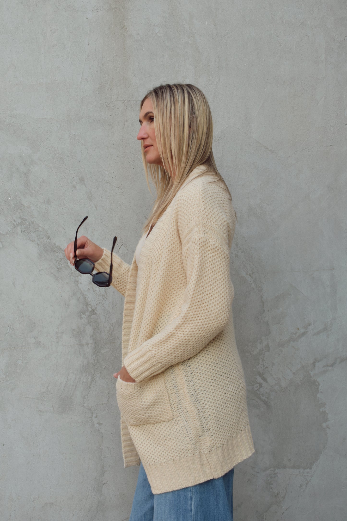 cream cardigan with front patch pockets, hangs straight , ribbed trim and hits mid thigh