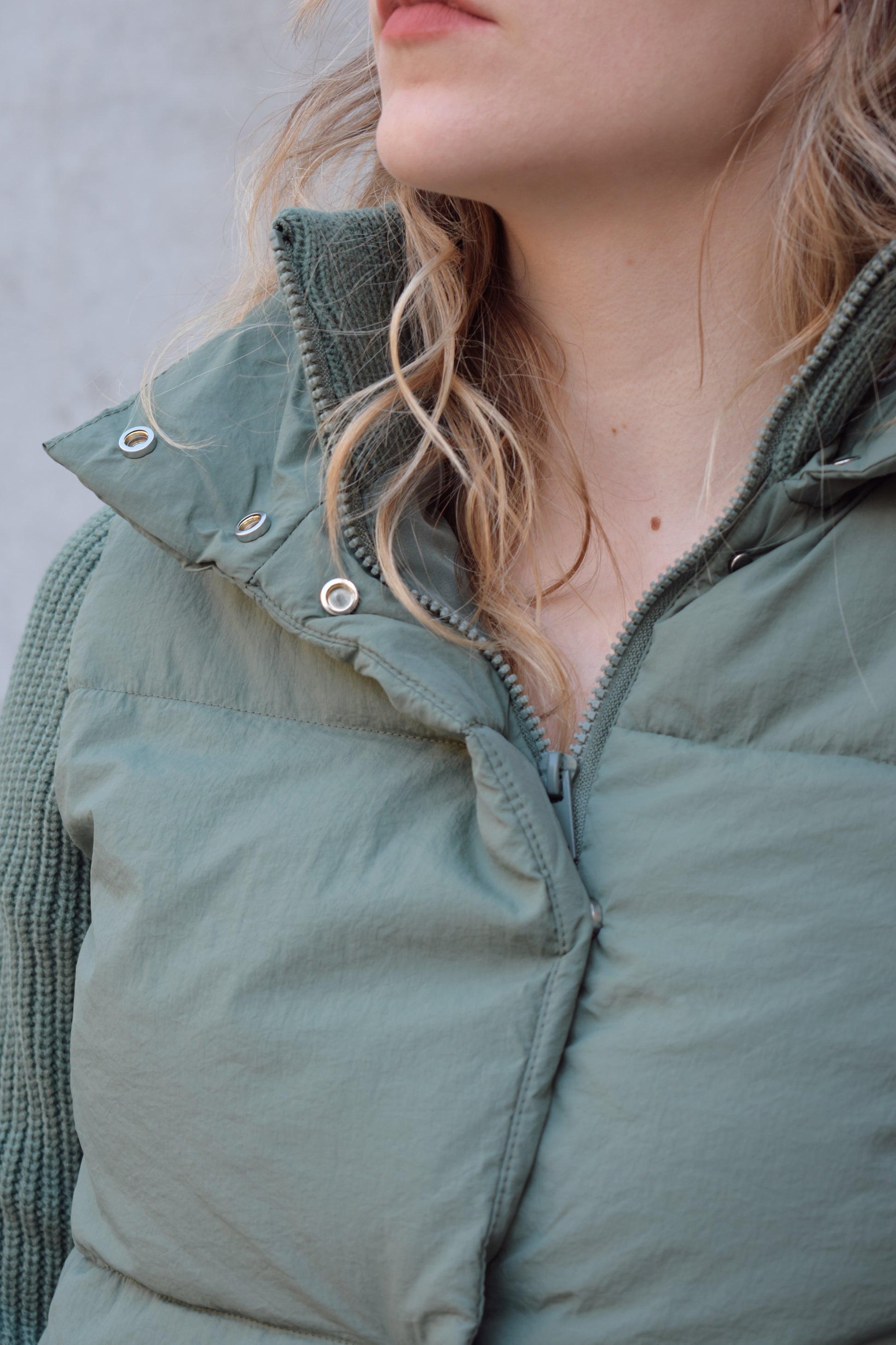 blue green puffer jacket with ribbed knit sleeves, zip and snap front enclosure, has double collar with both materials, has pockets, sinch band at hem