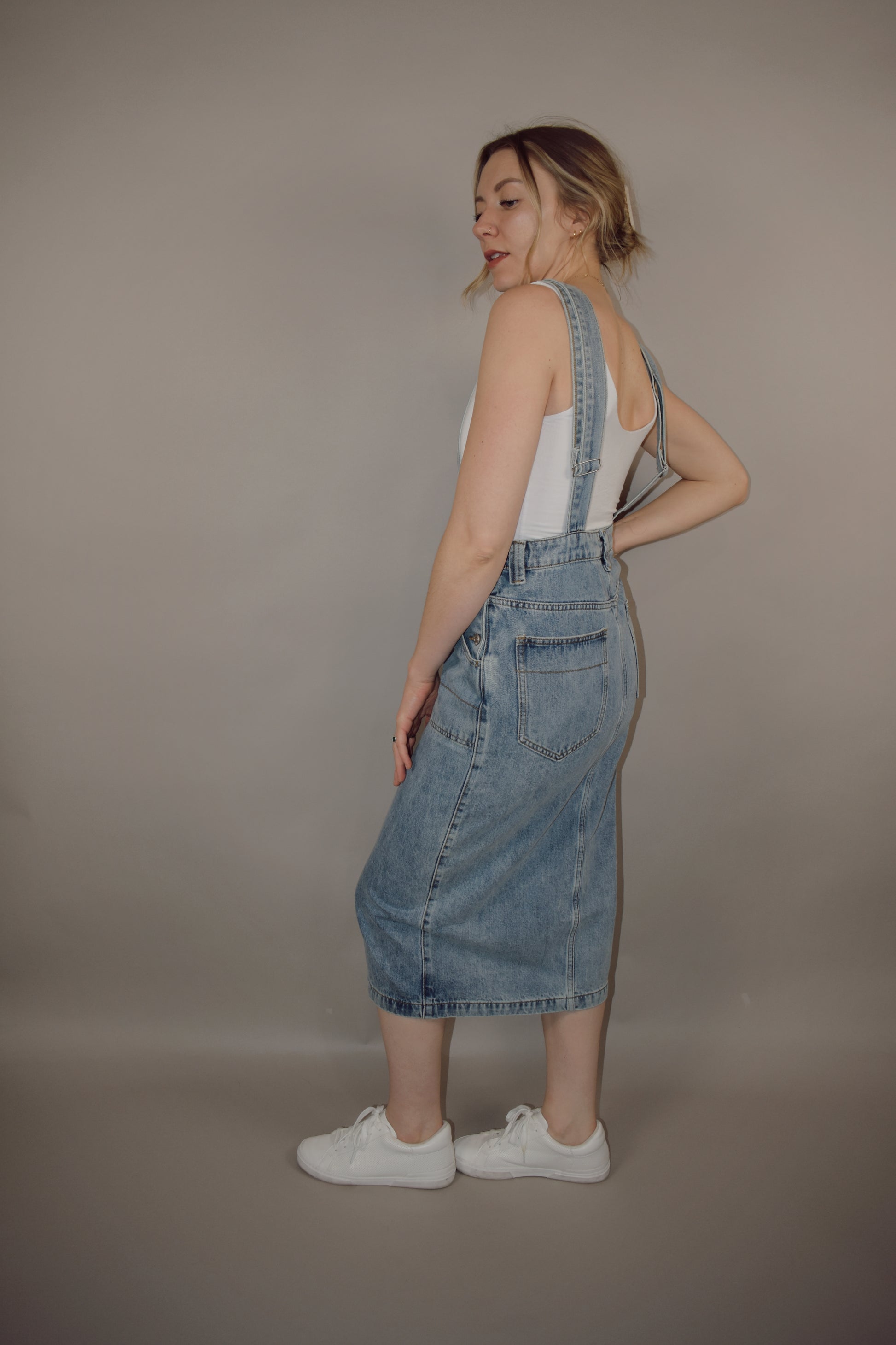light wash denim overall midi skirt dress with front slit, square neckline on front and back, adjustable straps, has beltloops, deep front pockets, back pockets, button enclosure on both sides