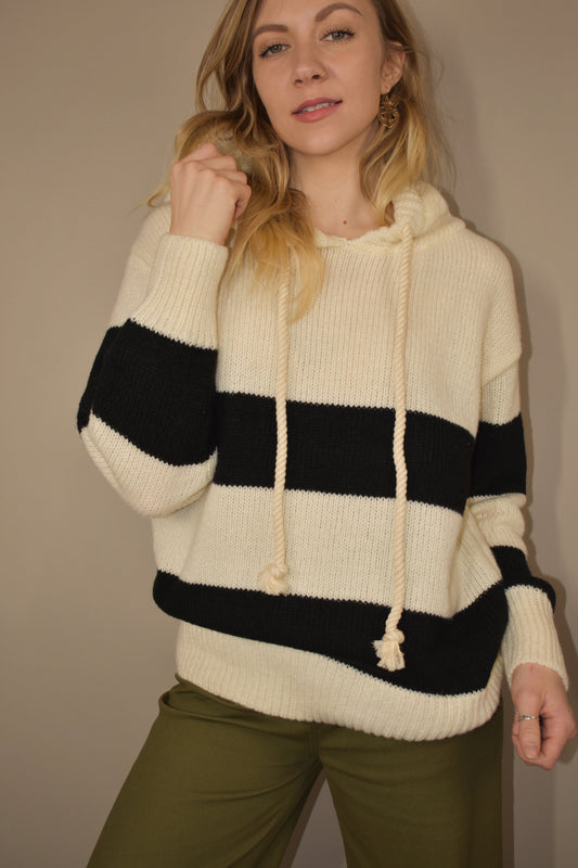 oversized knitted hoodie with two black stripes across the body and goes onto the arms
