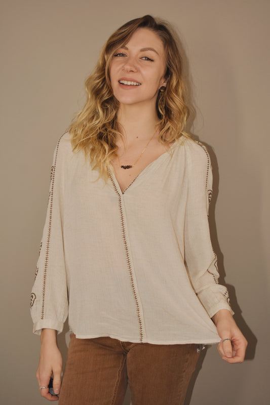 Cream colored v neck full length tunic with brown embroidered detailing down sides of arms and along hem that goes down the center front of the shirt. Flowy. Boho. 