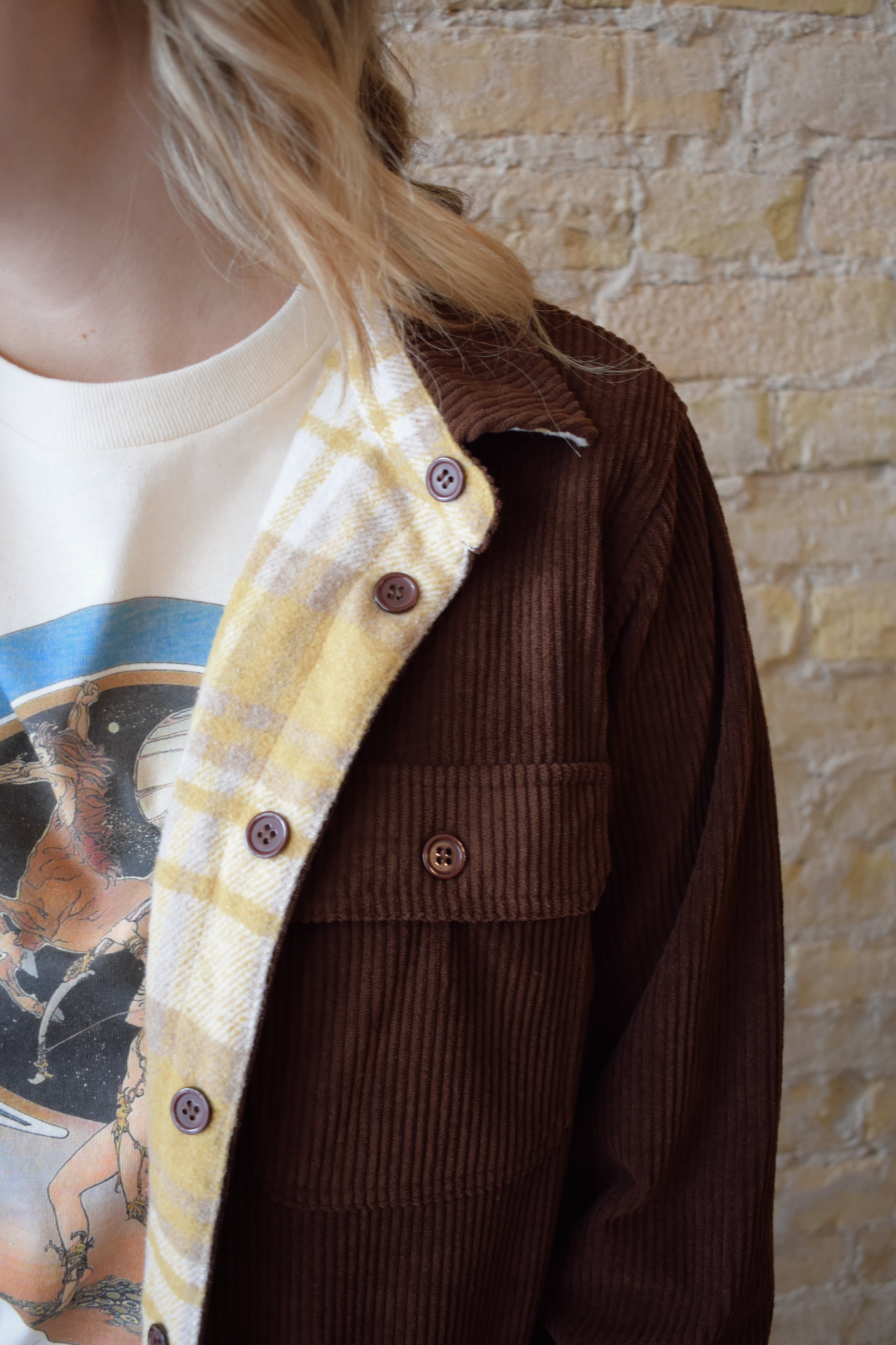 dark brown corduroy shacket lined with mustard color plaid flannel, reversible, one side has breast pockets the other has side front pockets, button down, relaxed fit full length