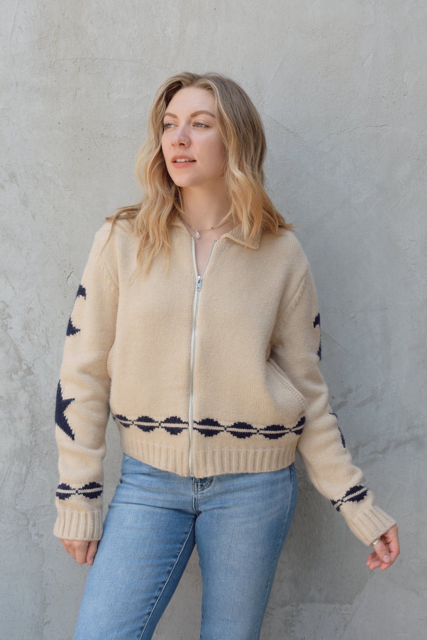 cream zip up sweater jacket with dark blue moon and stars on sleeves and trim design, collared neckline, ribbed hem and cuffs, side pockets, drop shoulders, relaxed fit