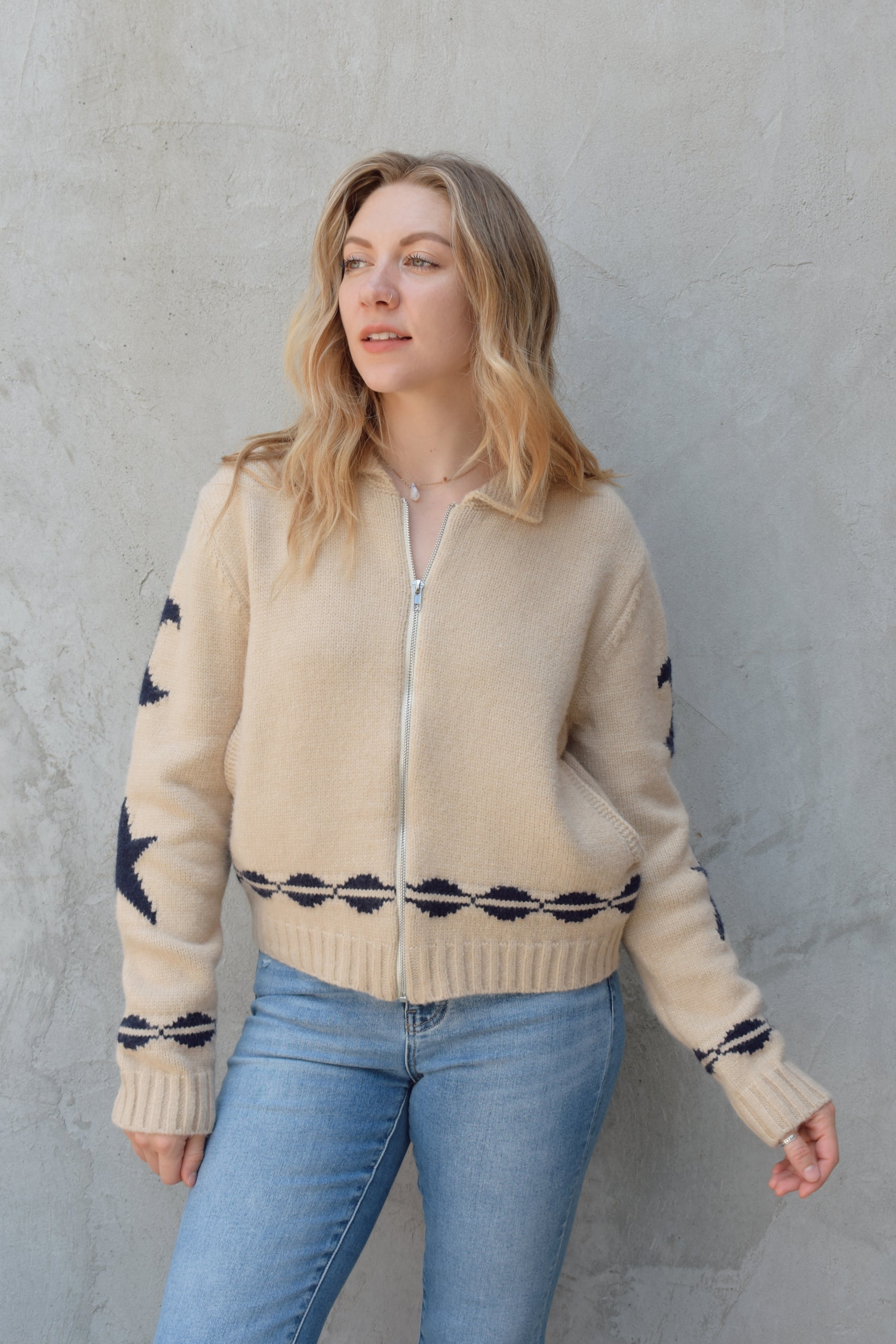 cream zip up sweater jacket with dark blue moon and stars on sleeves and trim design, collared neckline, ribbed hem and cuffs, side pockets, drop shoulders, relaxed fit