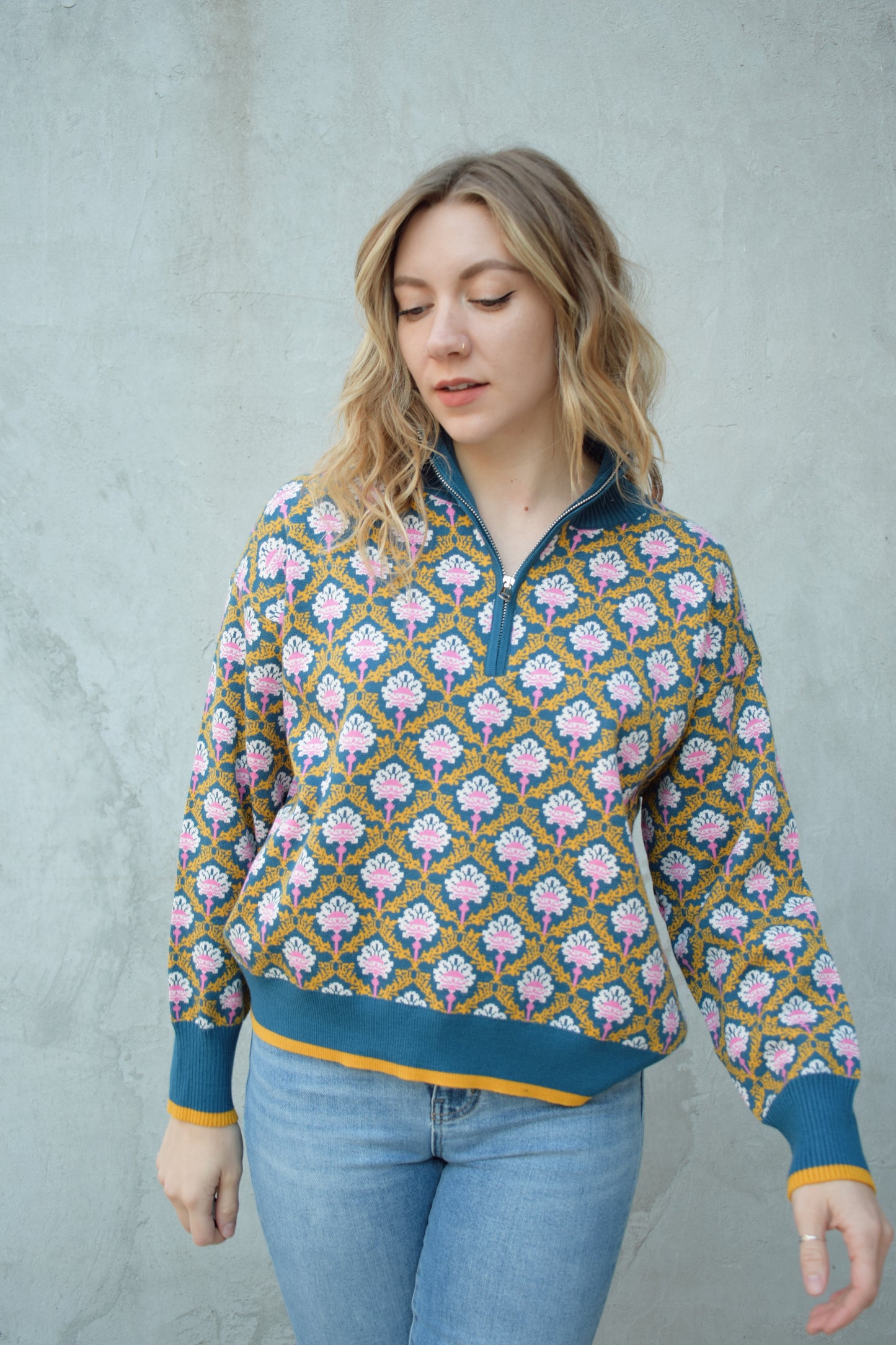 half zip relaxed fit statement pattern pullover with blue and yellow band at ham and cuff and just blue on collar. pattern is yellow, white, and pink on a blue background