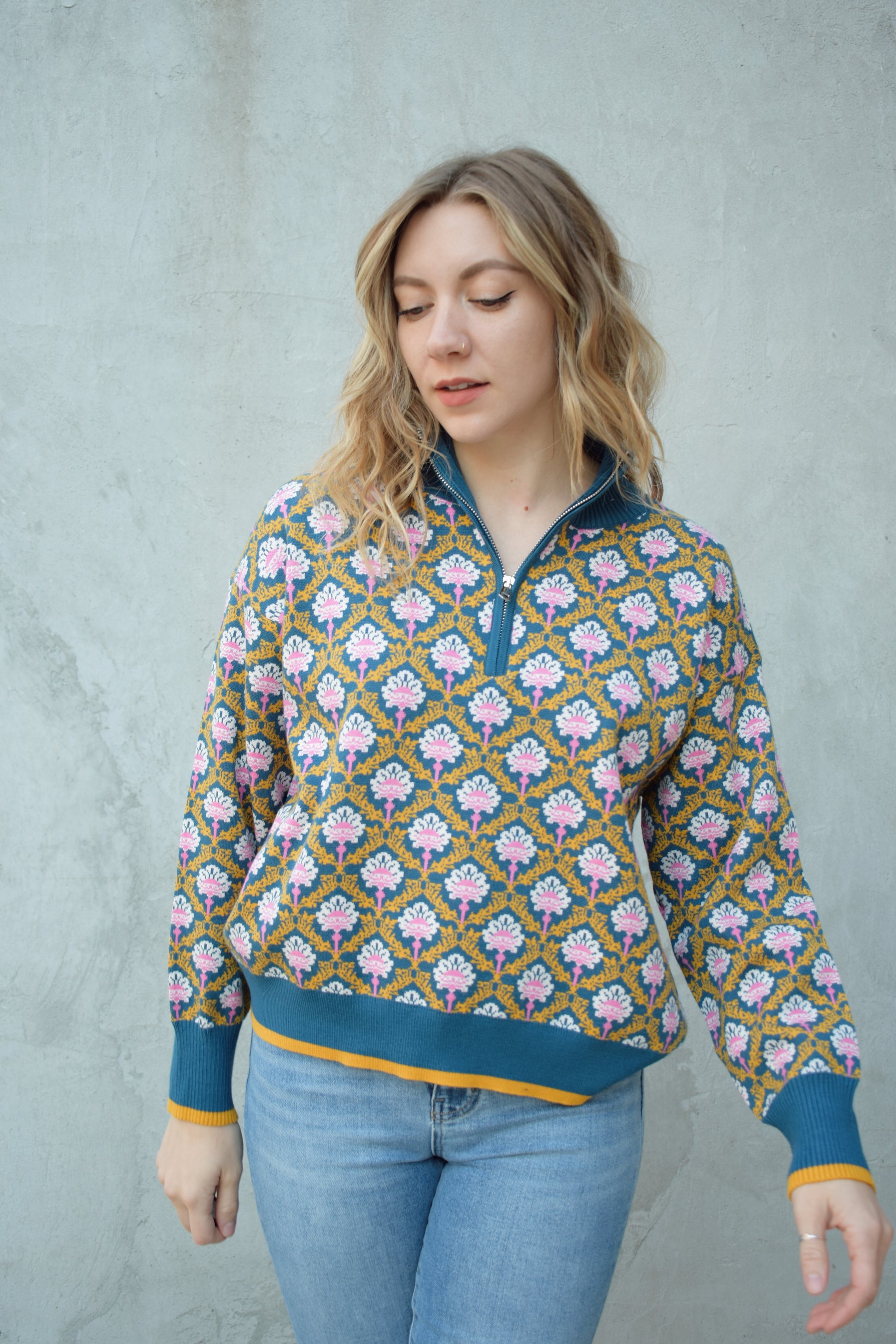 half zip relaxed fit statement pattern pullover with blue and yellow band at ham and cuff and just blue on collar. pattern is yellow, white, and pink on a blue background