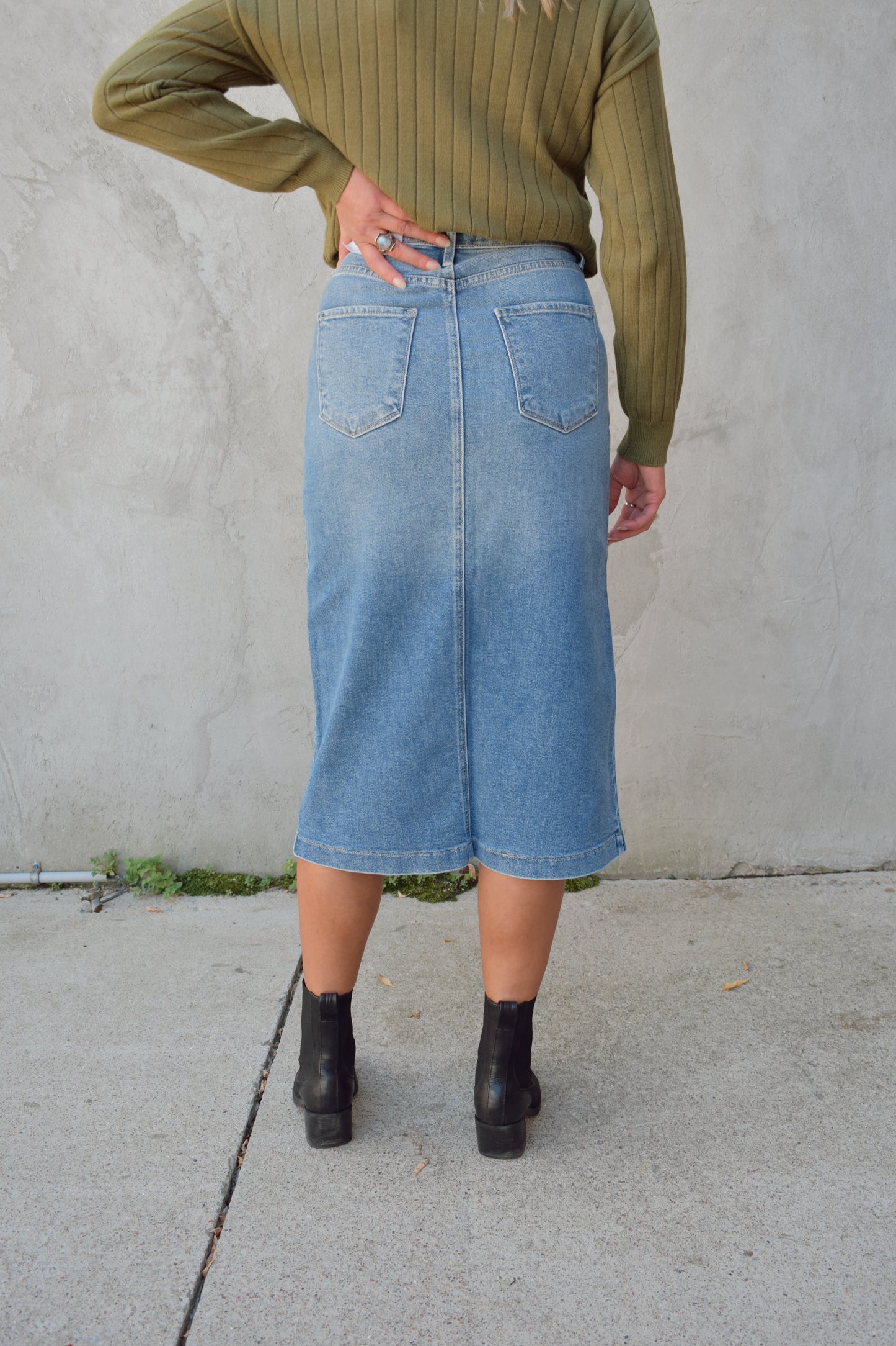 medium to light wash denim midi skirt with front slit, front patch pockets, zip and button enclosure, beltloops, back pockets, no distressing.