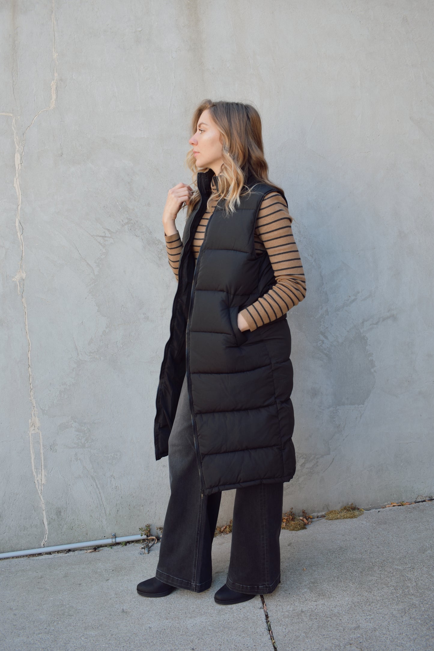 longline black puffer vest. front zip enclosure. has pockets. hits just below the knee.